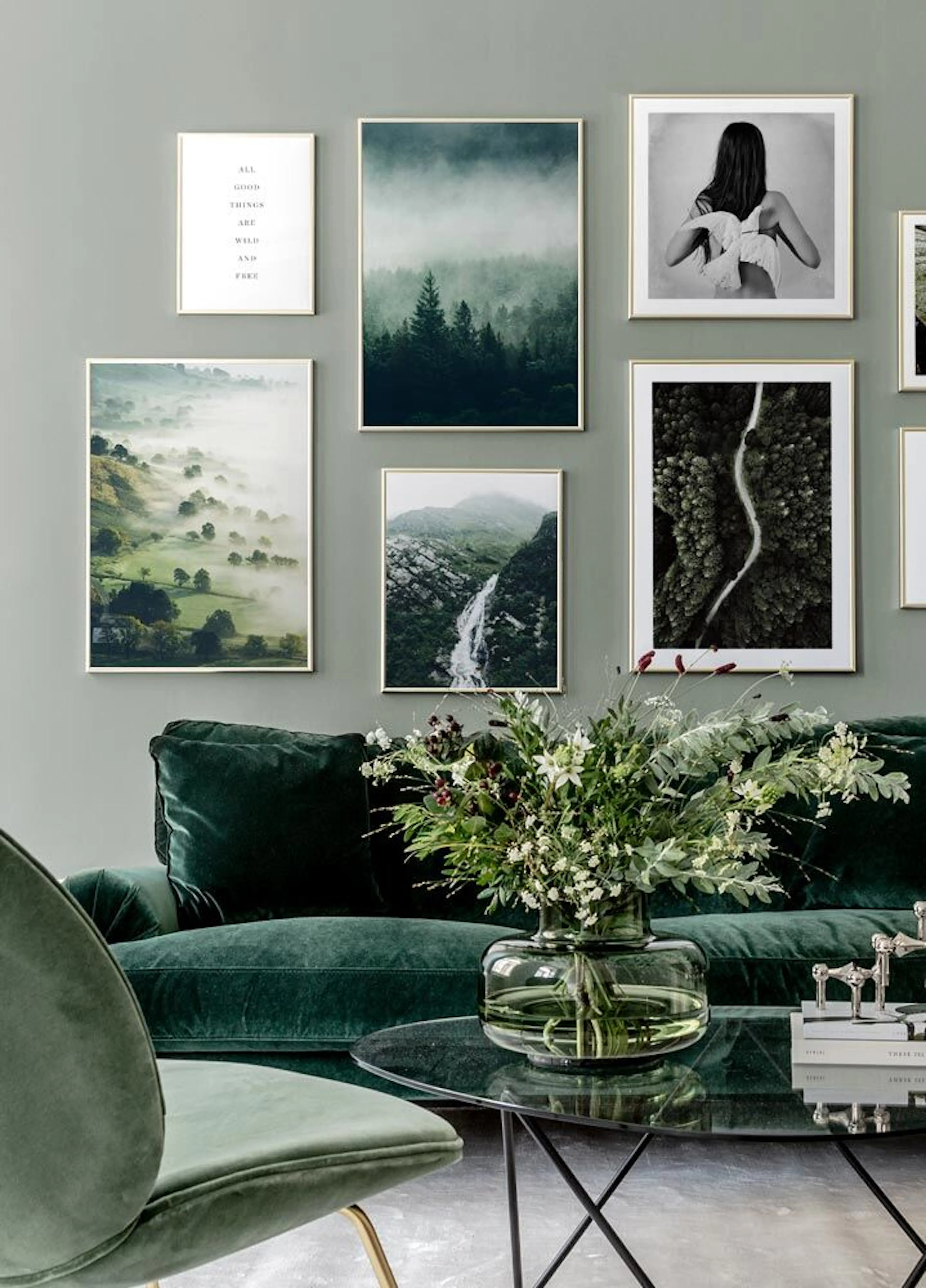 Nástěnná galerie plakátů s přírodními motivy a černobílou fotografií, visící nad zelenou sametovou pohovkou s květinami na konfe