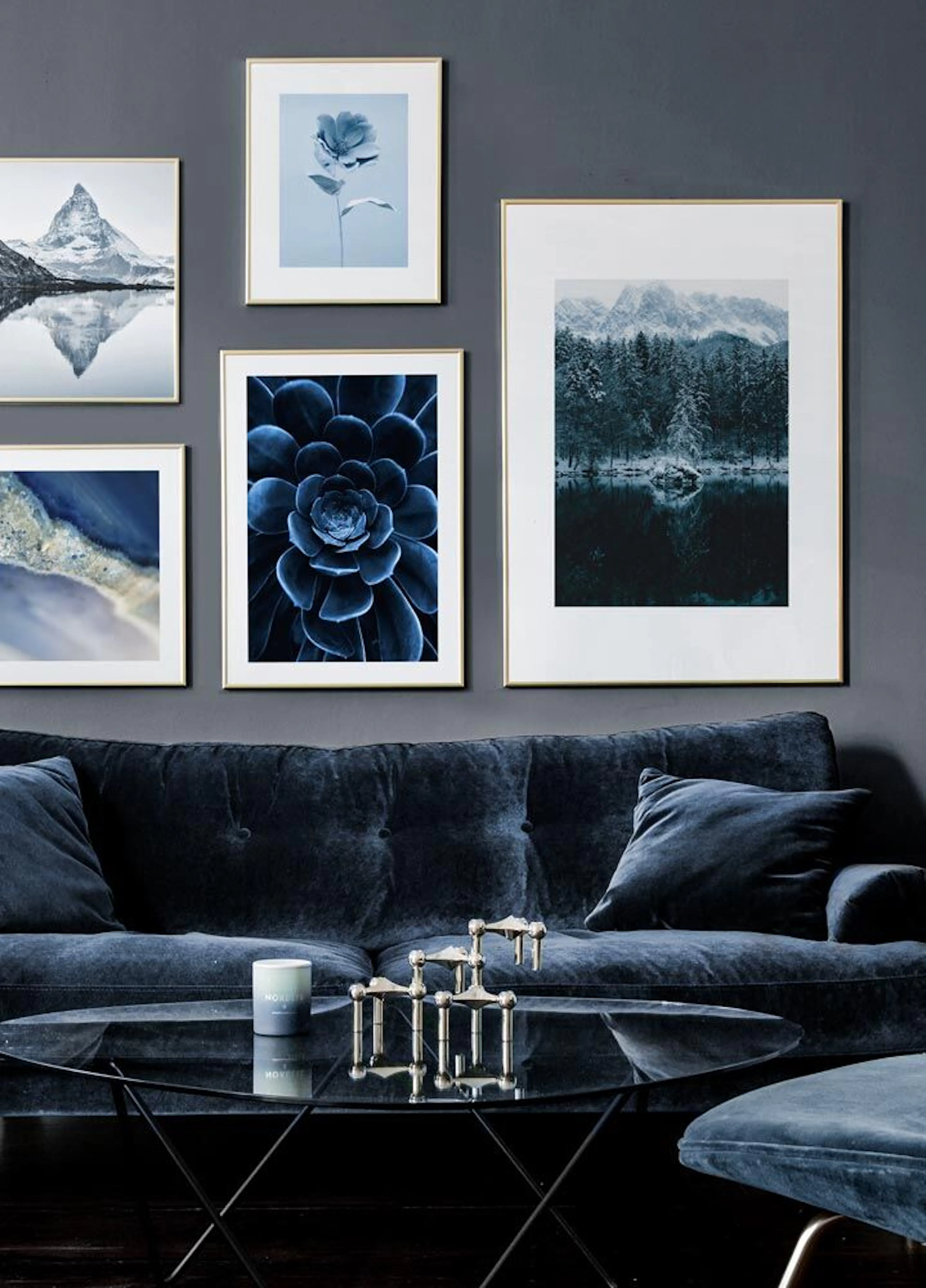 A gallery wall of blue-toned posters, including snowy mountains, a succulent, a flower, and abstract patterns, displayed above a