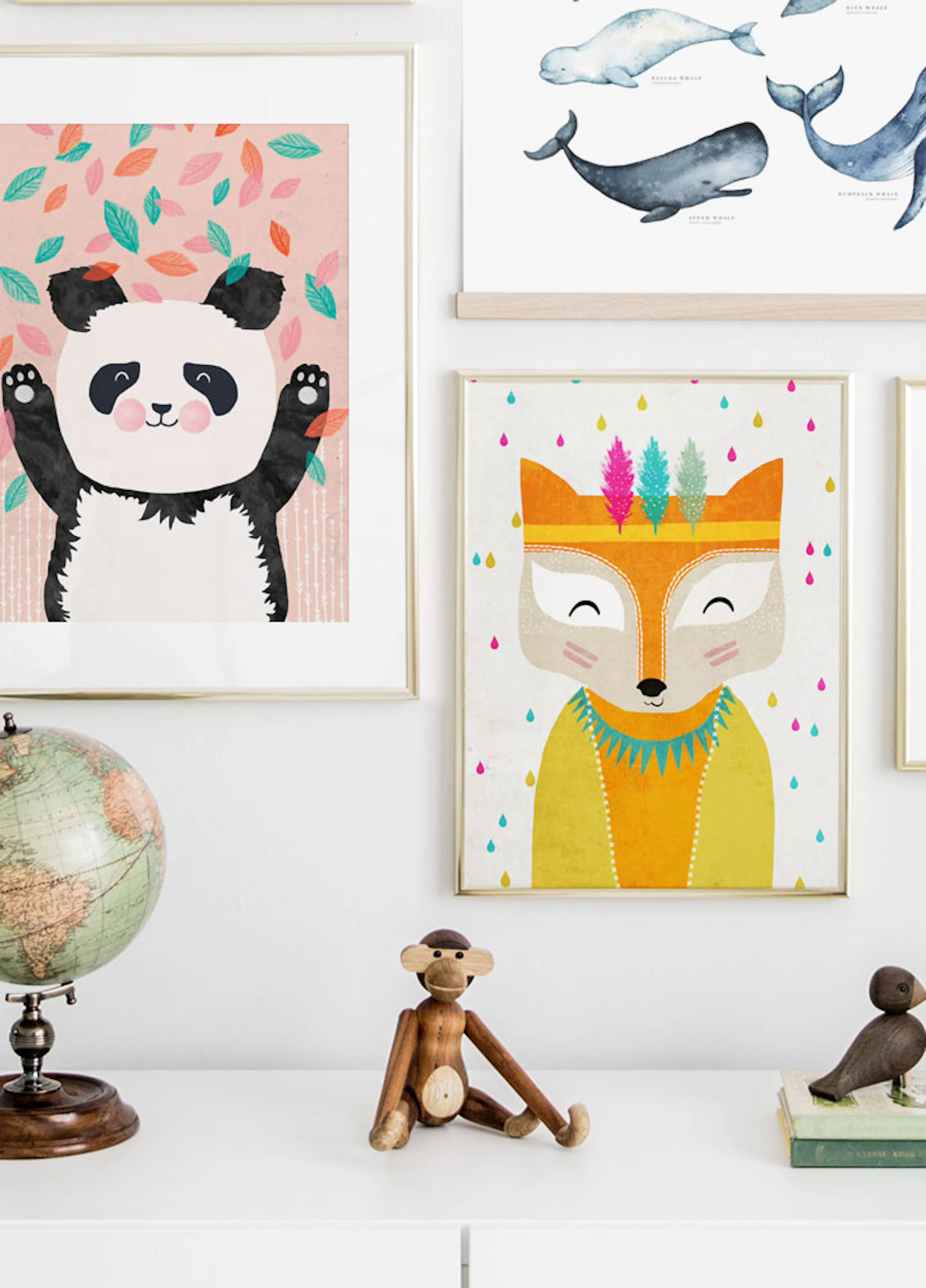 A cheerful cartoon panda with raised paws and falling leaves, displayed in a gallery wall arrangement above a white dresser with