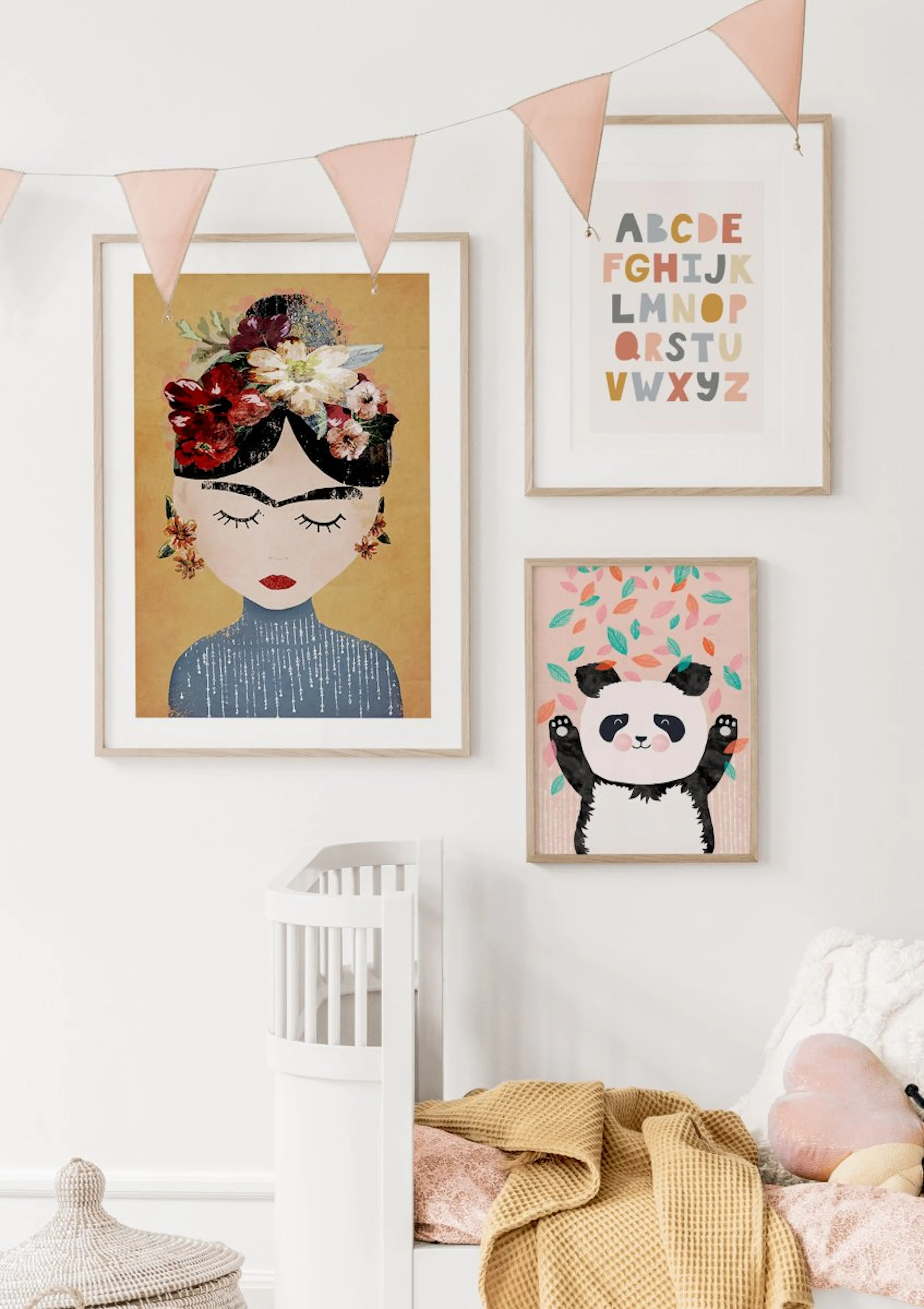 A gallery wall with three prints in a nursery. The largest print features a woman with flowers in her hair, next to an alphabet 