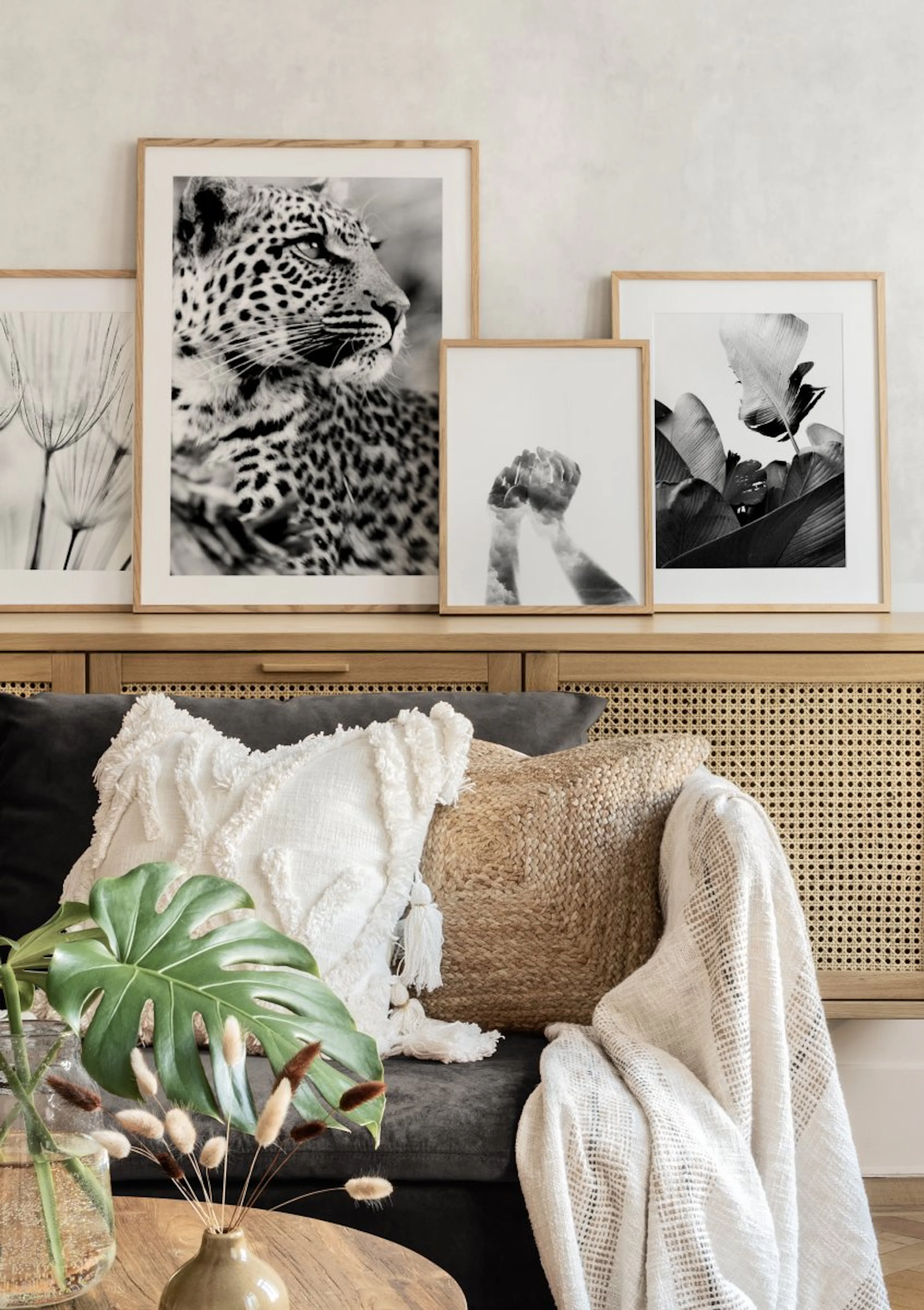 Neljä mustavalkoista julistetta, joissa kuvataan leopardi, voikukka, kädet ja kasvinlehtiä, aseteltuna lipaston päälle moderniss