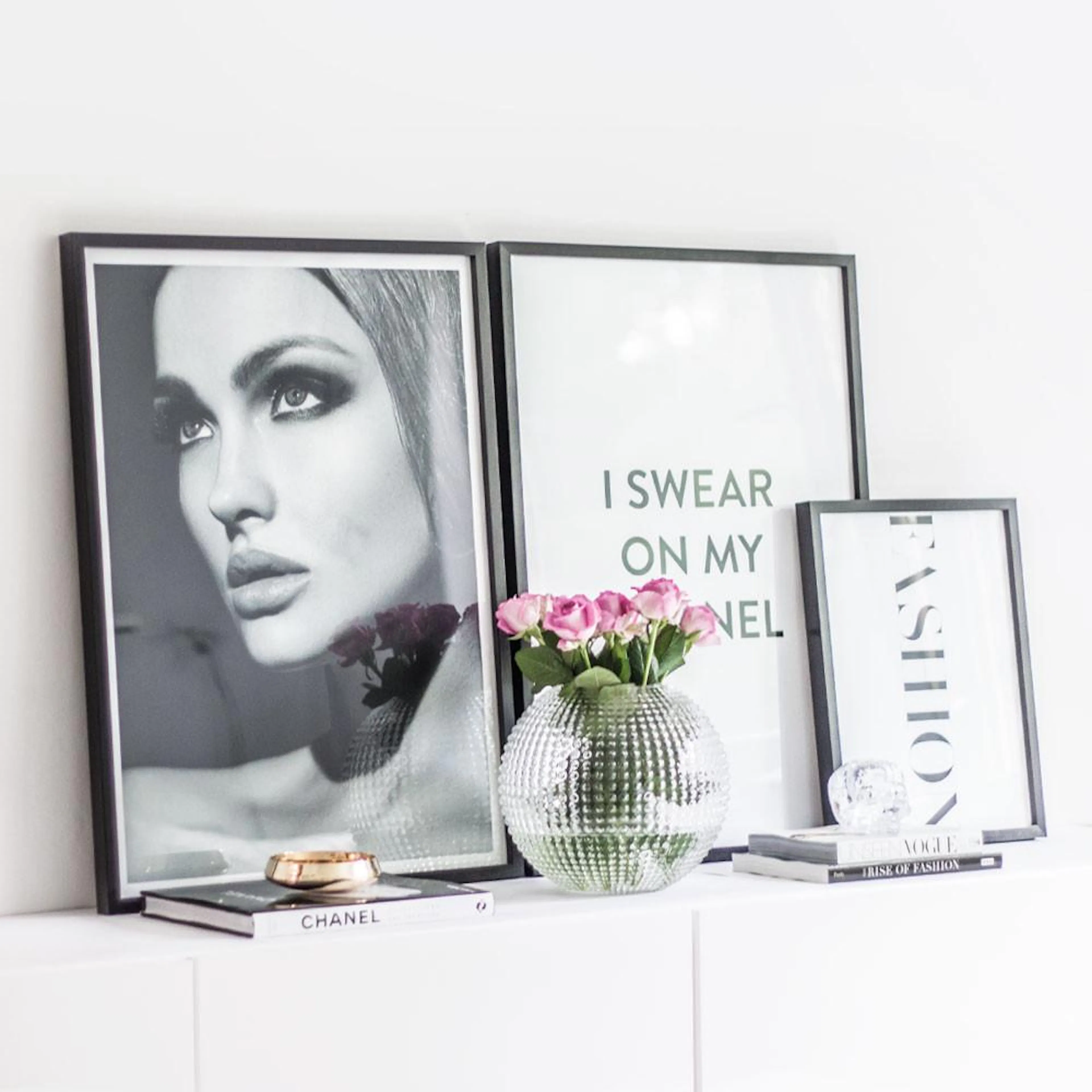 Three fashion posters displayed on a white cabinet: a black and white portrait, a text poster, and a vertical FASHION poster.