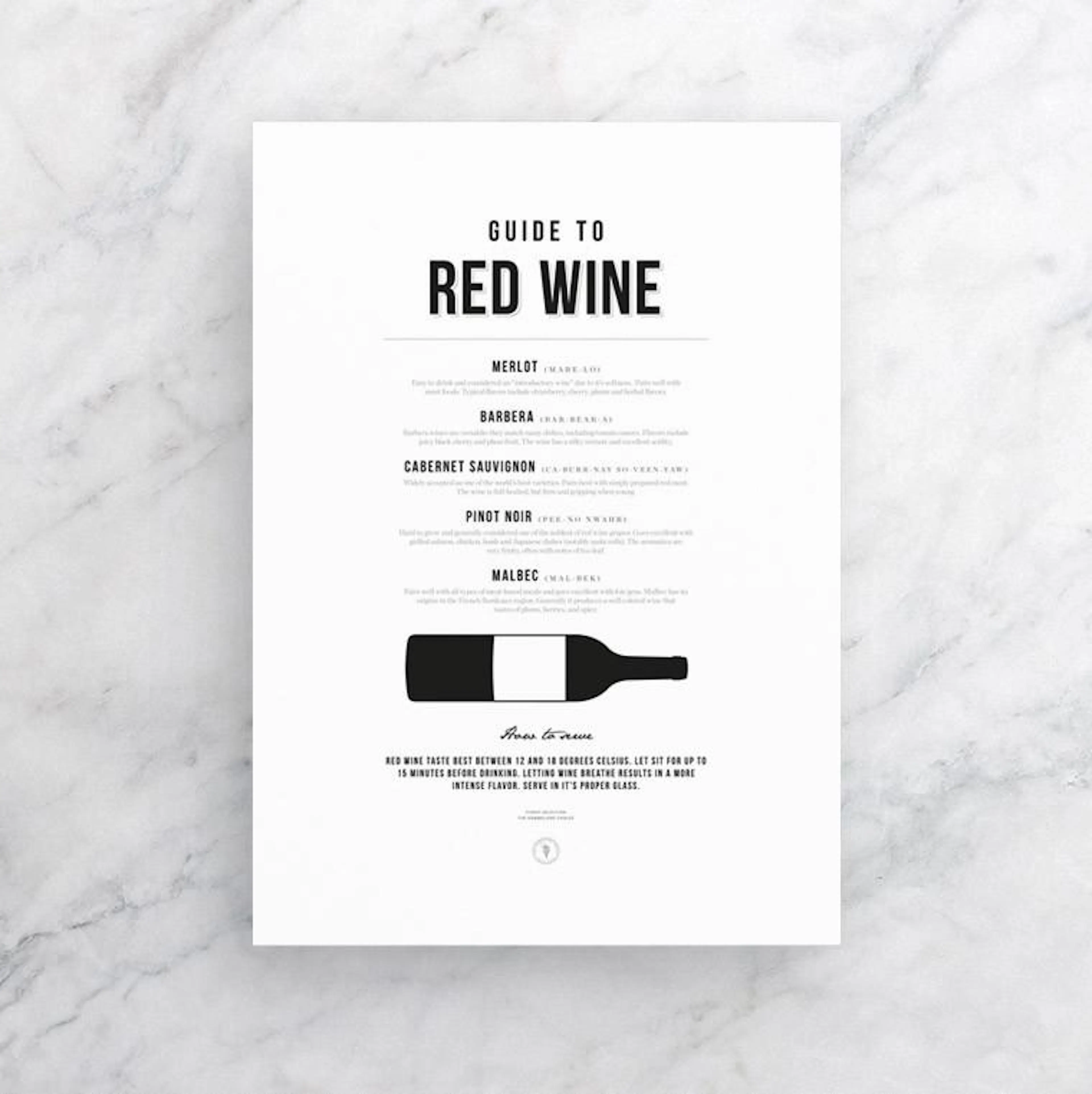 A white poster with a Guide to Red Wine listing wine types, descriptions, and serving tips, displayed on a textured surface.