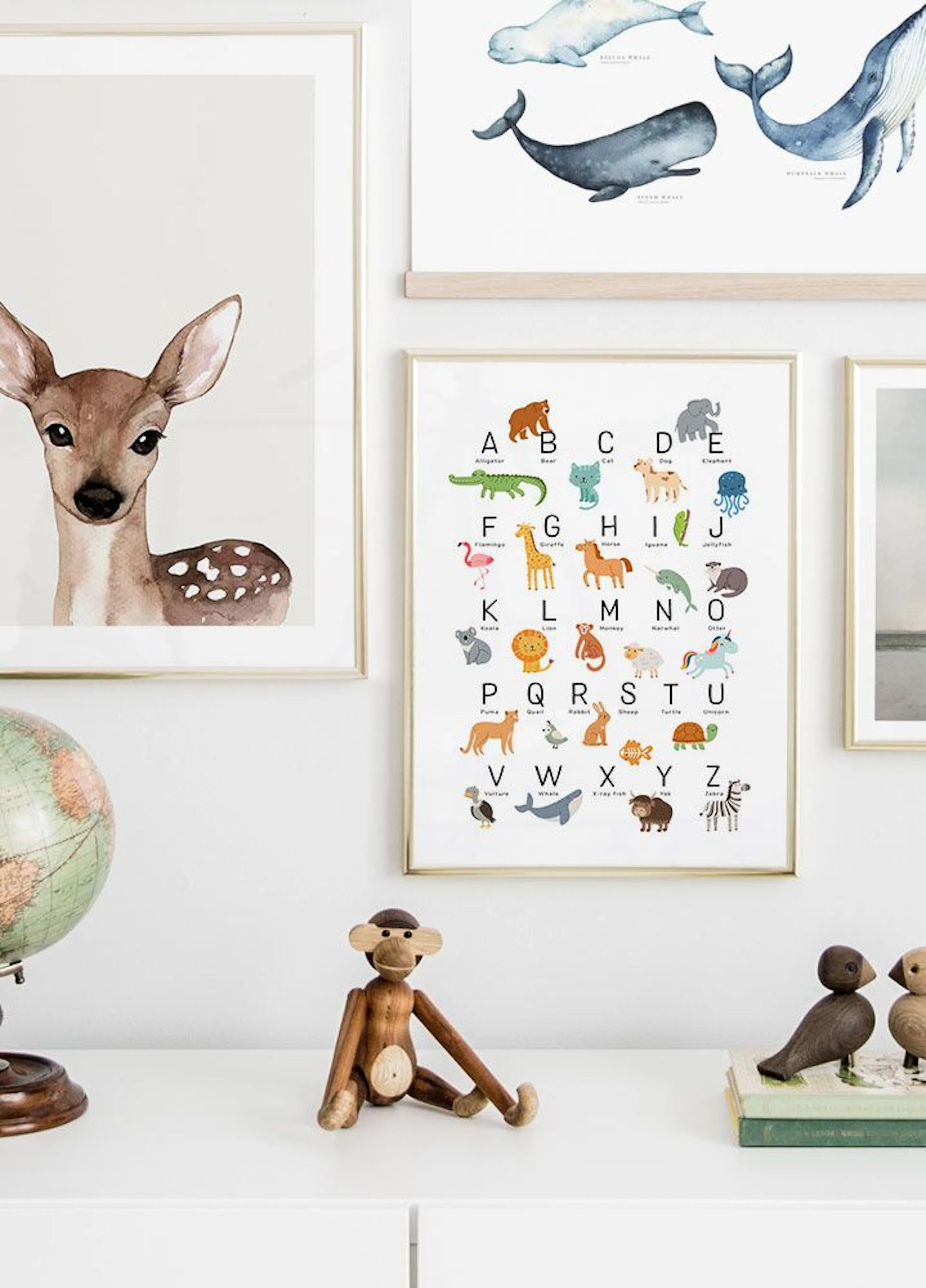 A colourful animal alphabet display poster, with a deer poster and whale poster on a white wall in a childs room.
