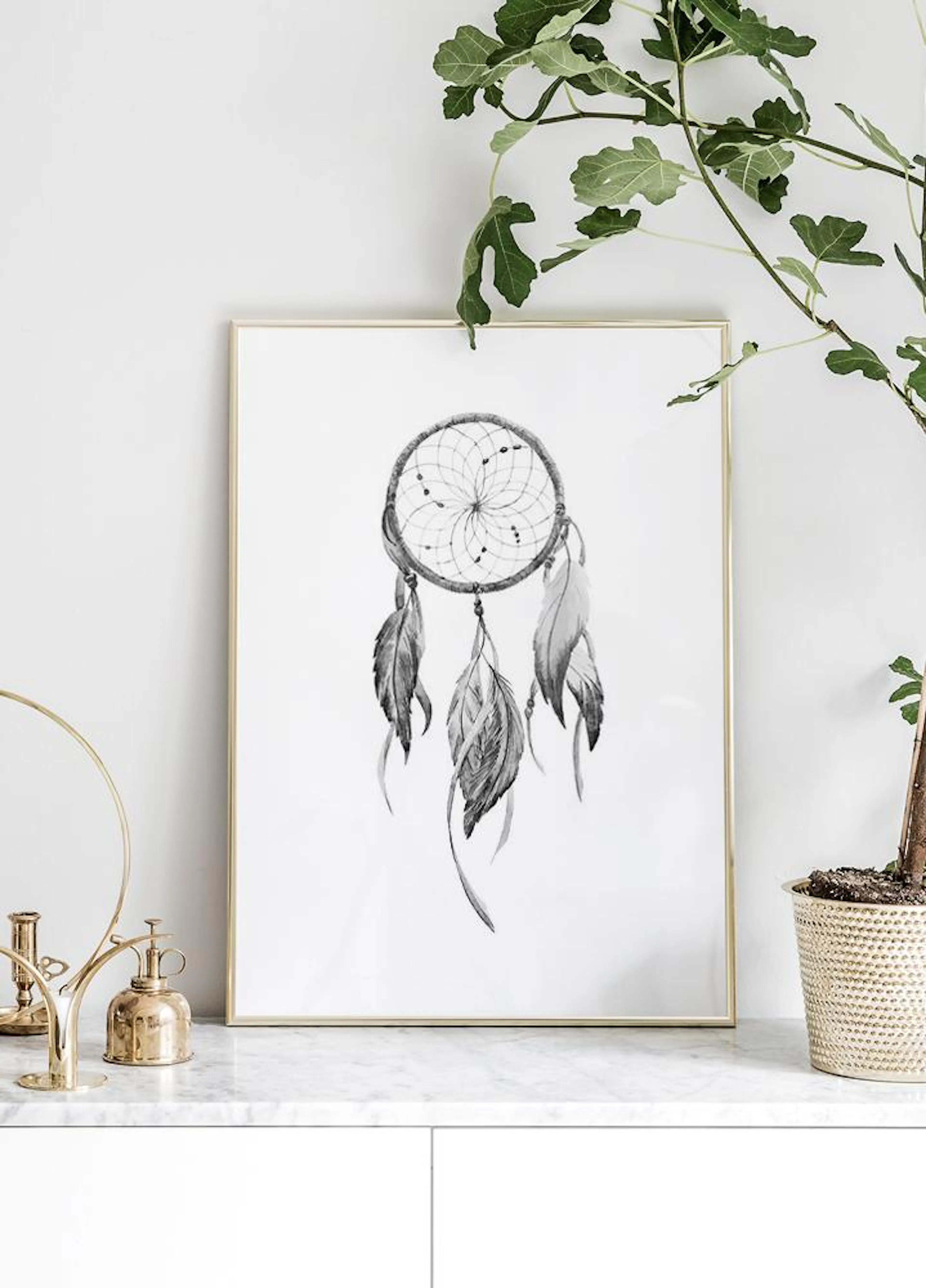 Monochrome dreamcatcher poster with feathers displayed on a white marble surface next to a plant.