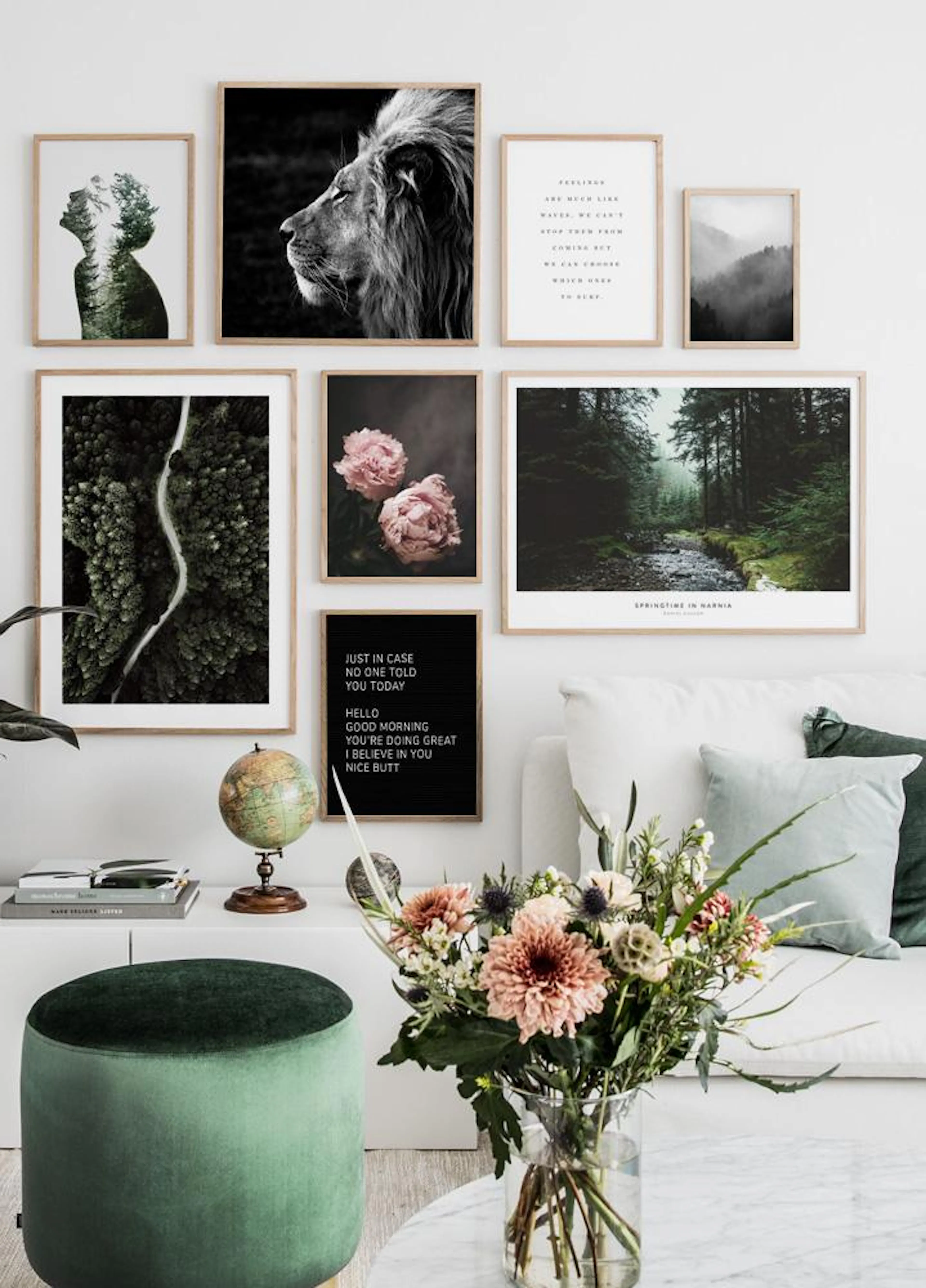 A gallery wall featuring nature-themed posters, including a lion, forest road, and peonies, hanging above a white sofa with gree