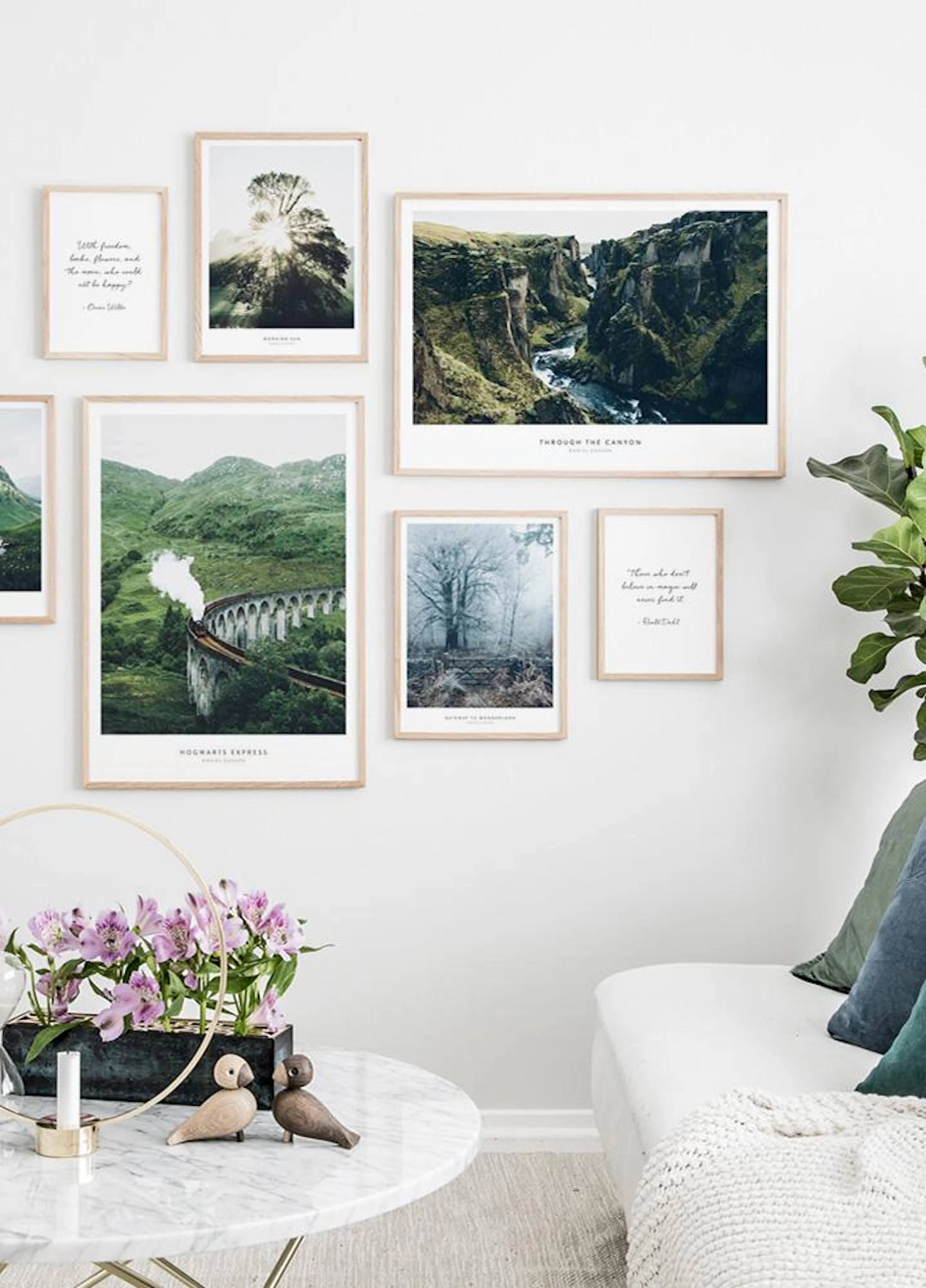Galleria a parete di poster con paesaggi naturali, come un canyon e un ponte con treno, in un soggiorno moderno.