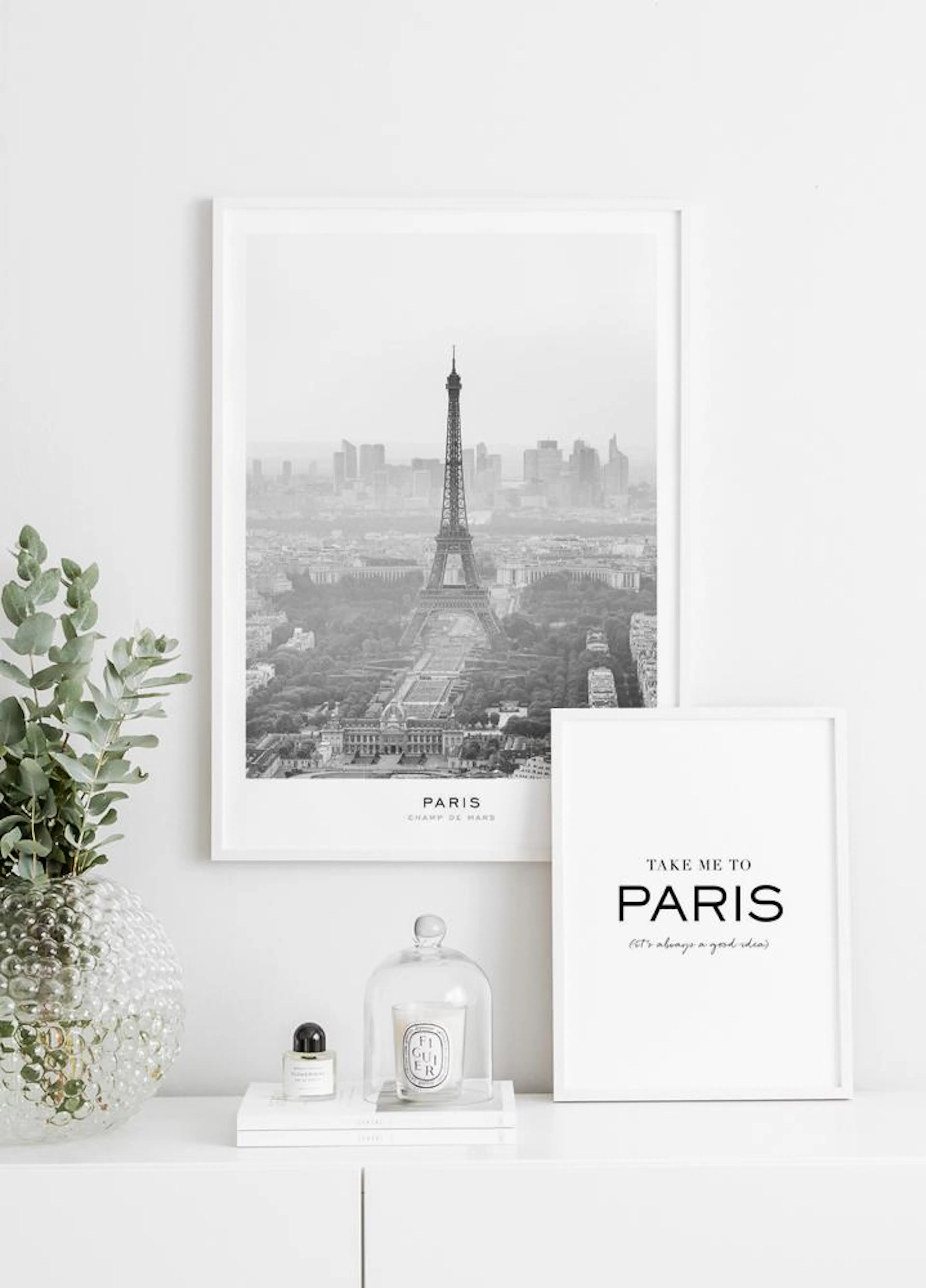 A black and white poster of the Eiffel Tower and Paris cityscape, displayed on a white console table with a plant and home décor