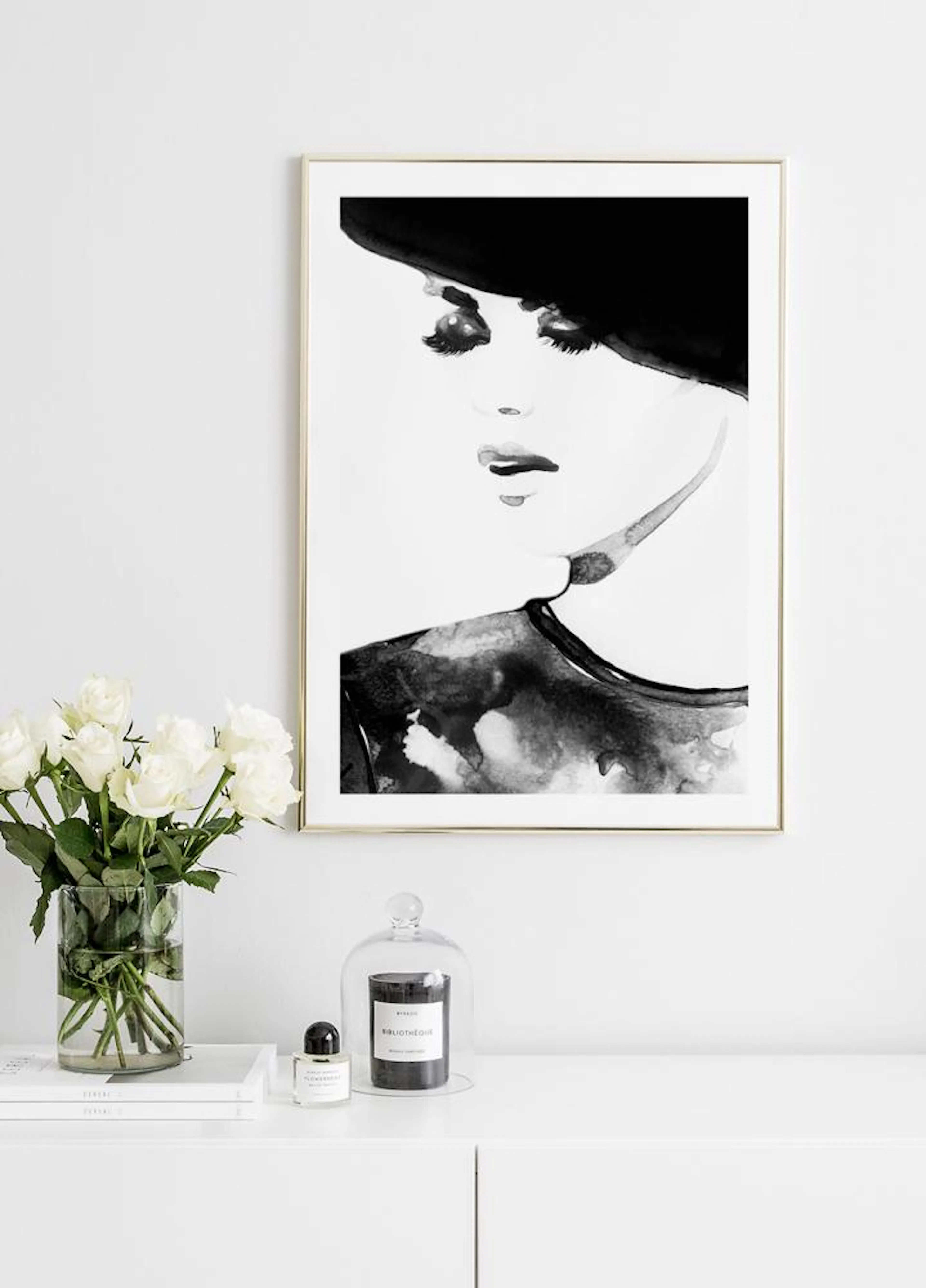 Fashion illustration featuring a woman in a black hat, displayed above a white chest of drawers with white roses and a candle.