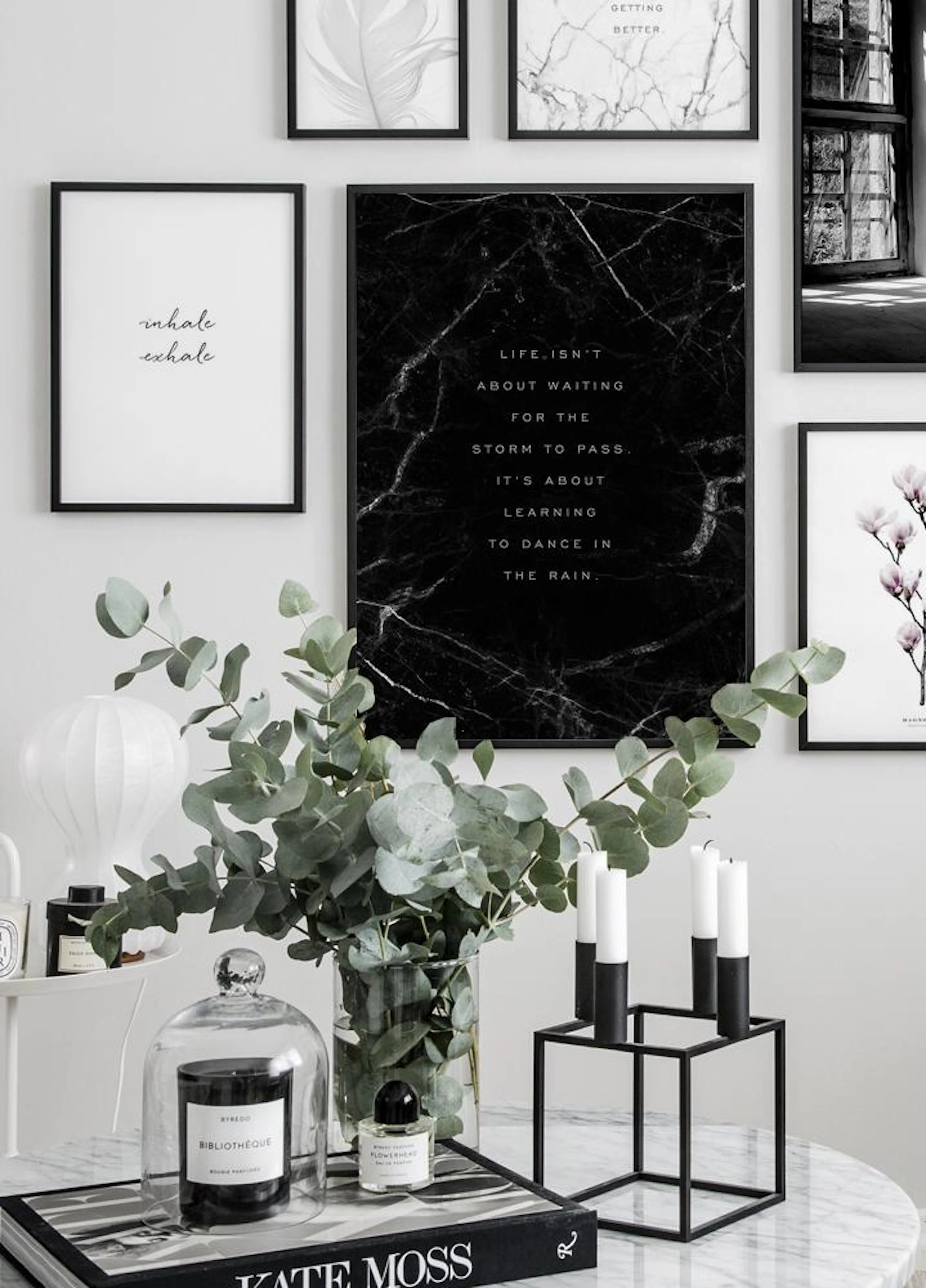 A gallery wall featuring a black marble poster with text, Life isnt about waiting for the storm to pass. Its about learning to d
