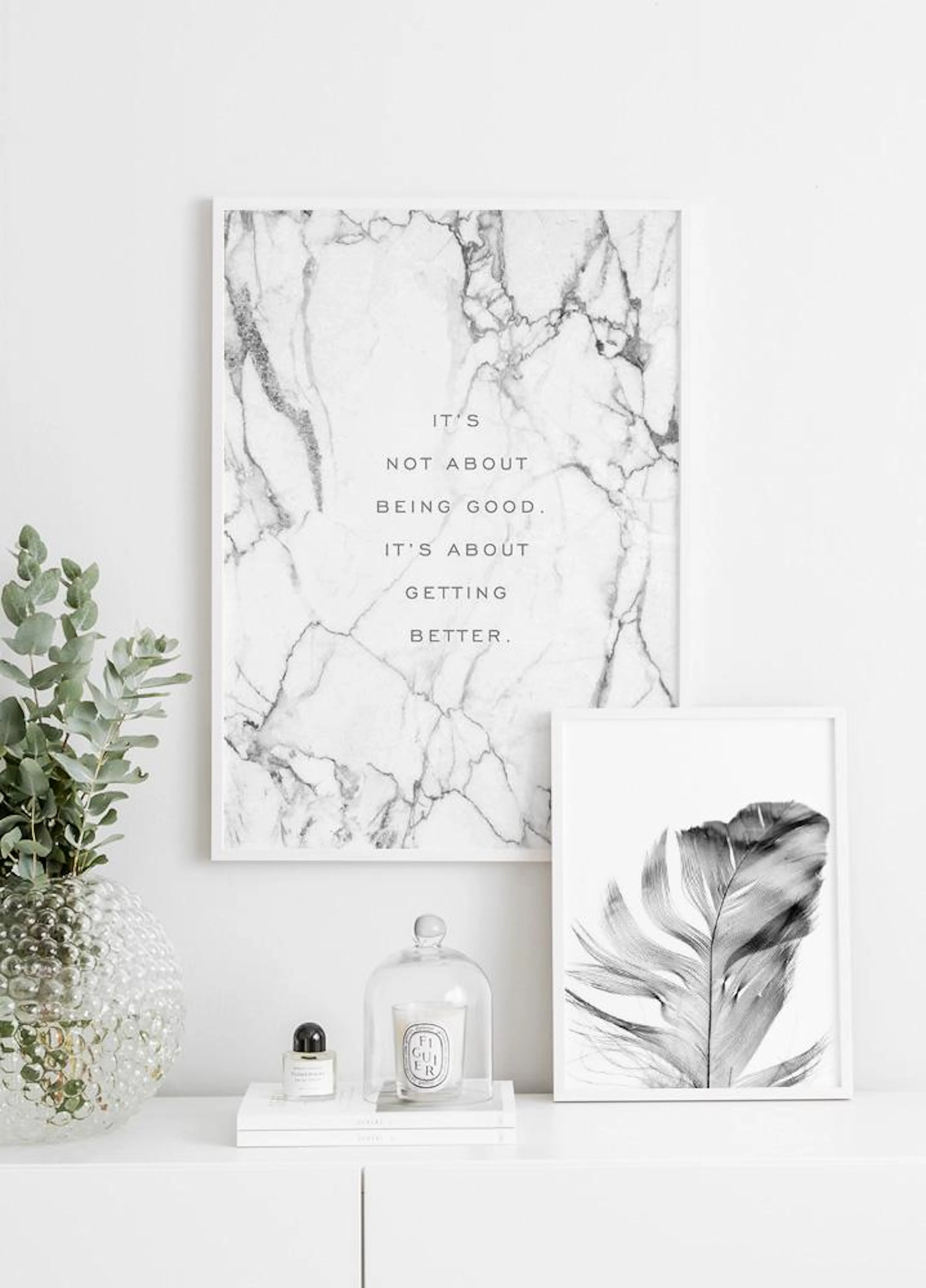 Poster con testo motivazionale su sfondo effetto marmo bianco, appeso ad una parete bianca sopra una cassettiera.