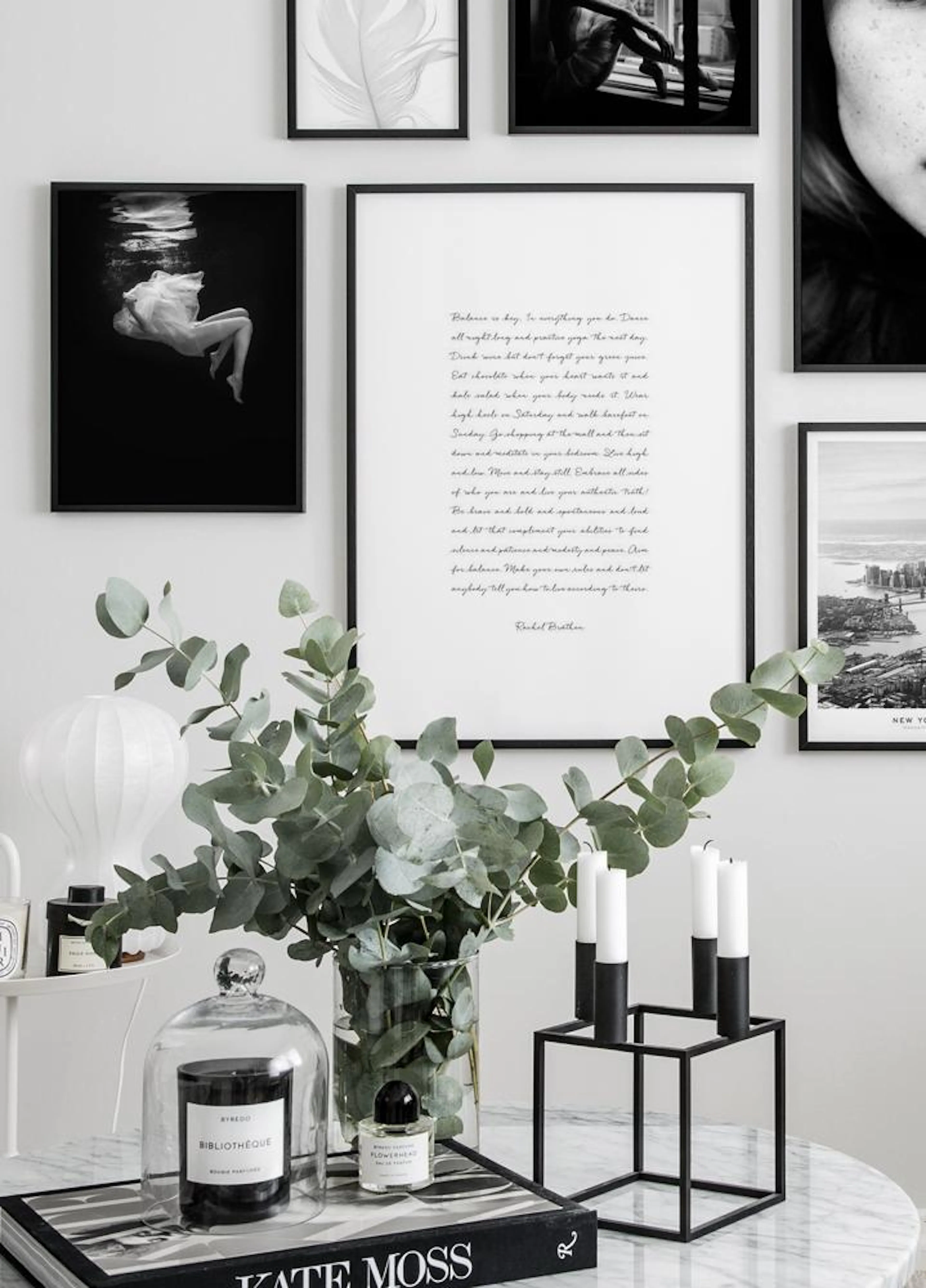 A gallery wall featuring a black and white poster of a woman in flowing fabric underwater, alongside a minimalist text poster, h