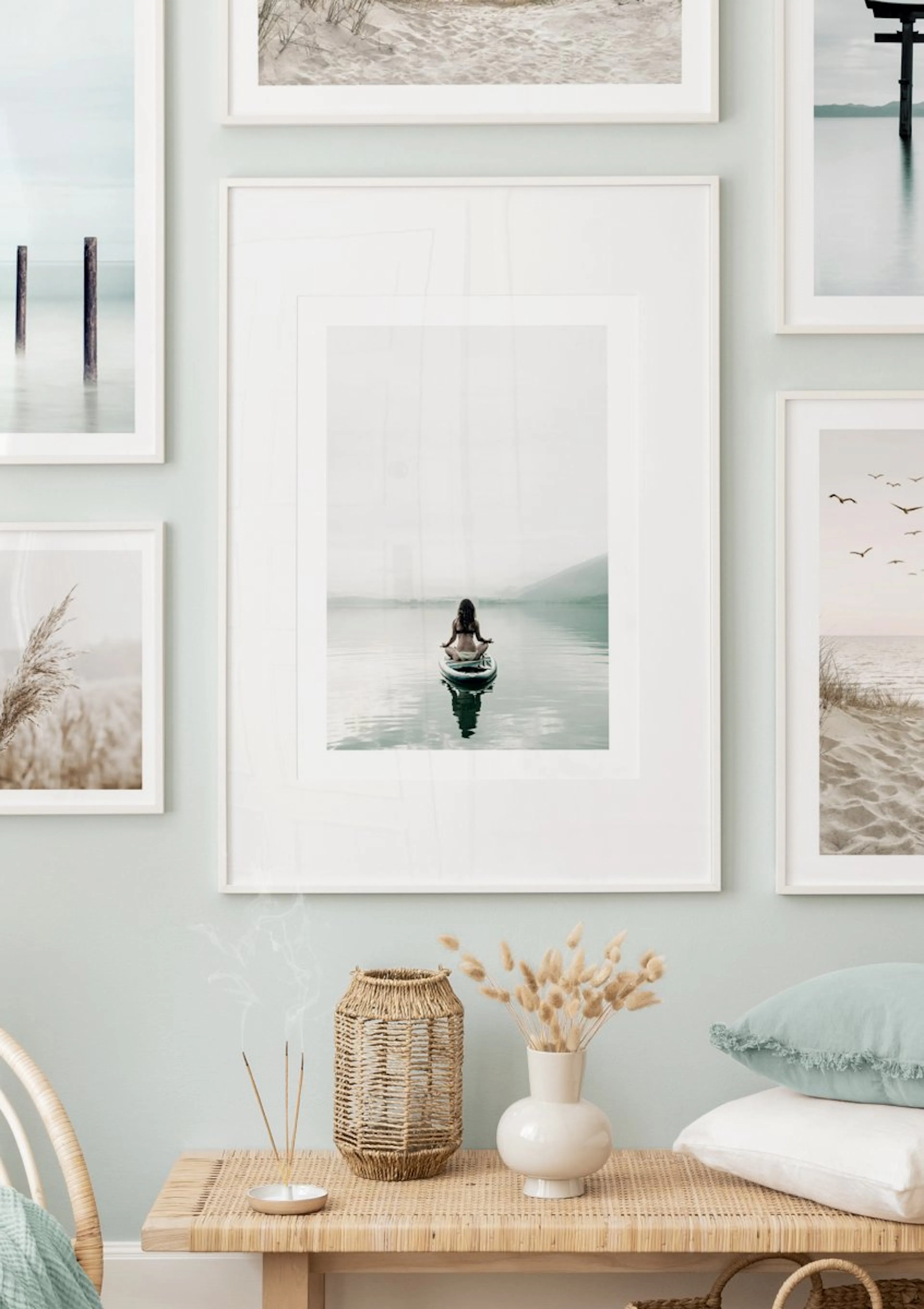 A gallery wall with a central poster of a person meditating on a paddleboard on a serene lake, surrounded by other nature-themed