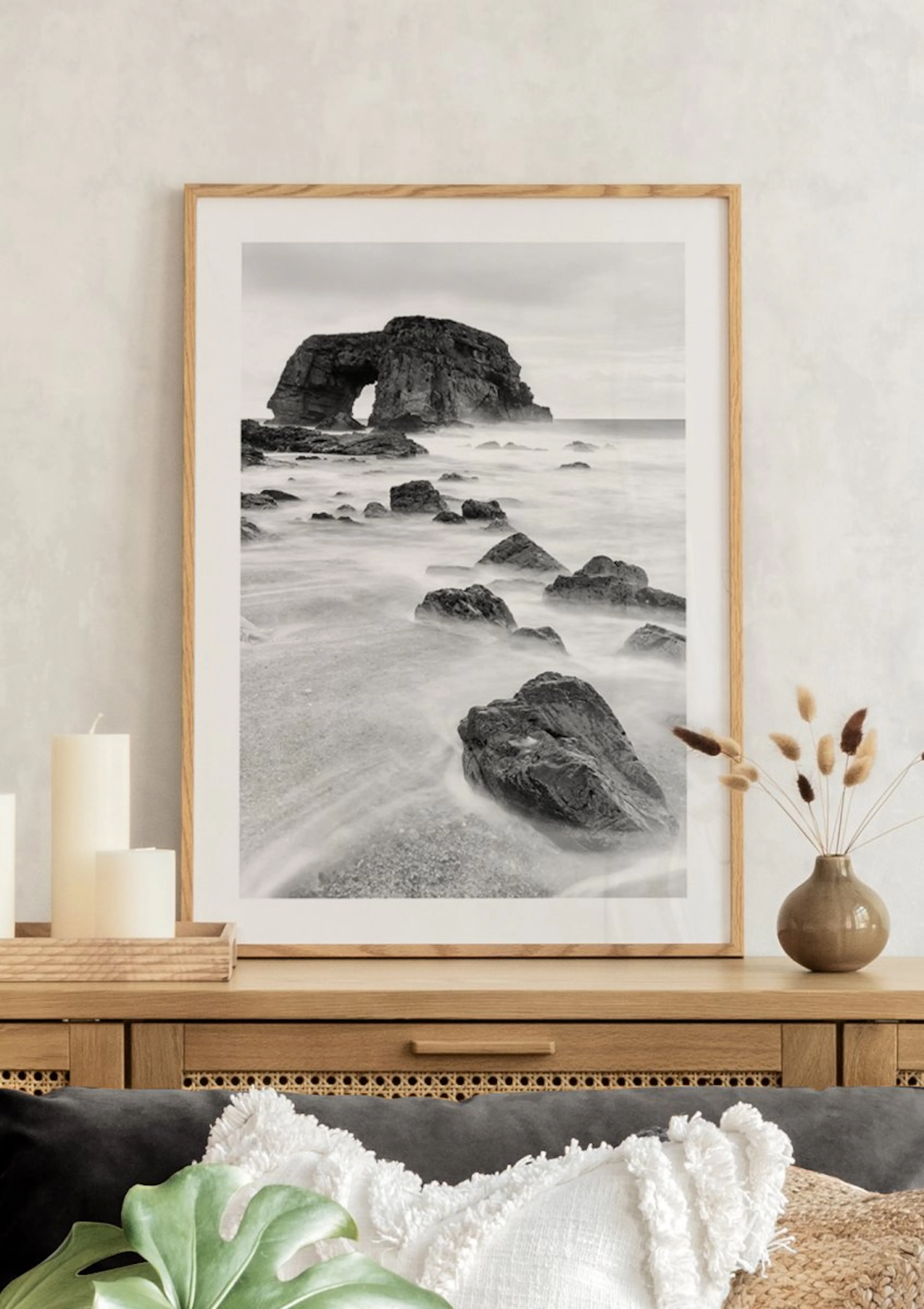 A stunning black and white coastal poster featuring a natural rock arch, with smooth water flowing over rocks on a sandy beach, 