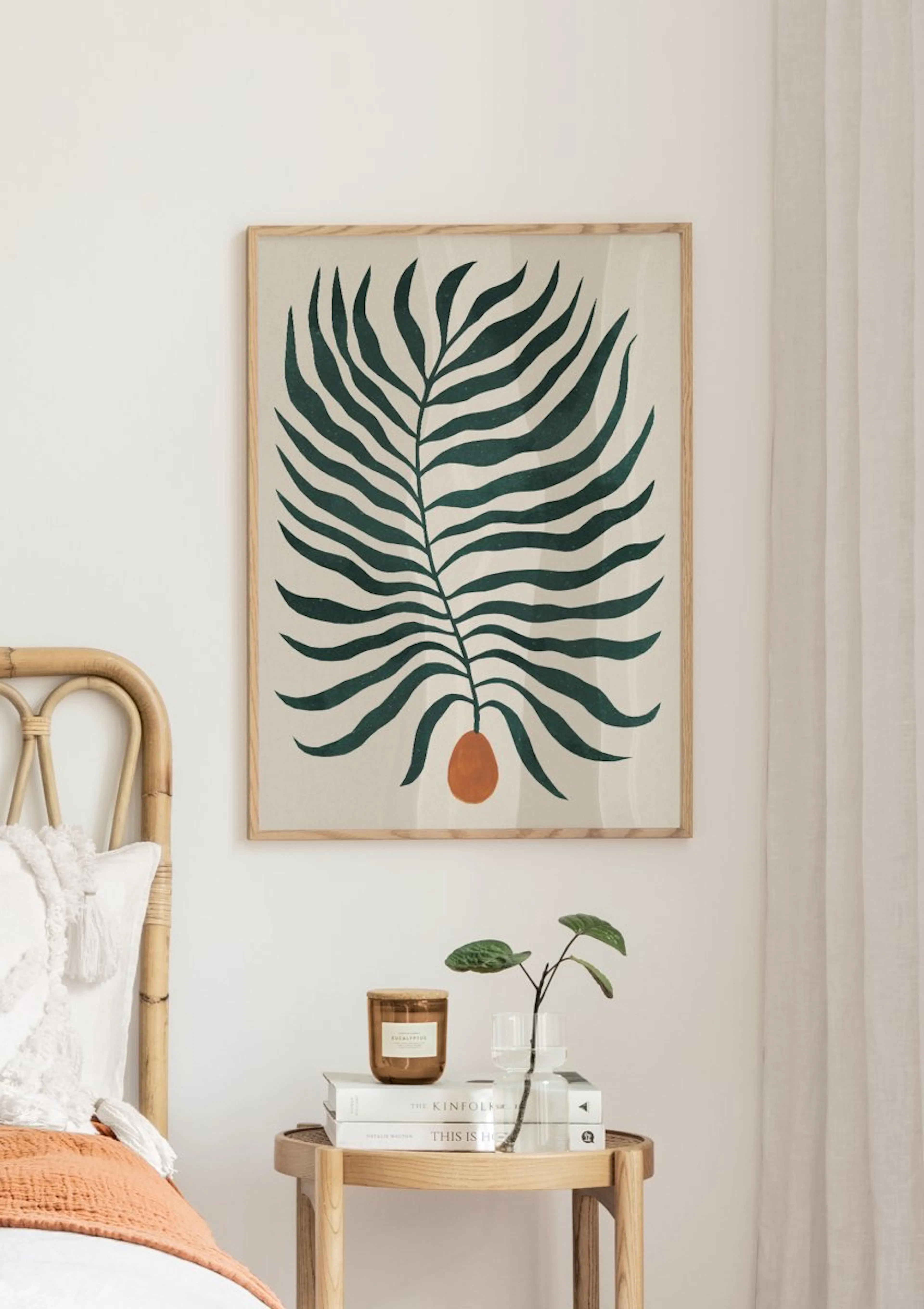 Botanical poster with a dark green palm frond and orange fruit on a light background, hanging above a bedside table in a bedroom