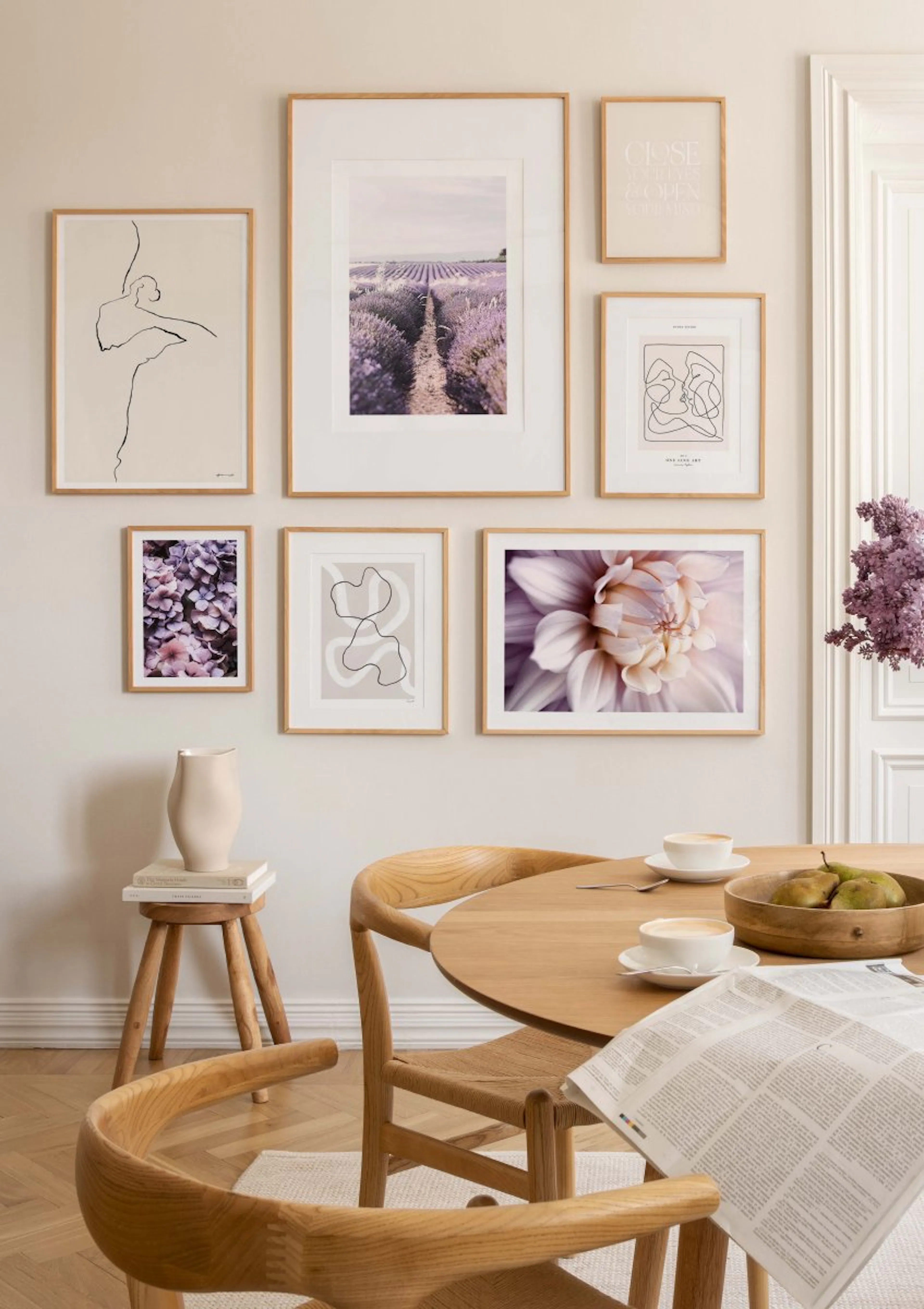 A gallery wall of posters in a dining room, featuring a lavender field, abstract line art, and floral prints.