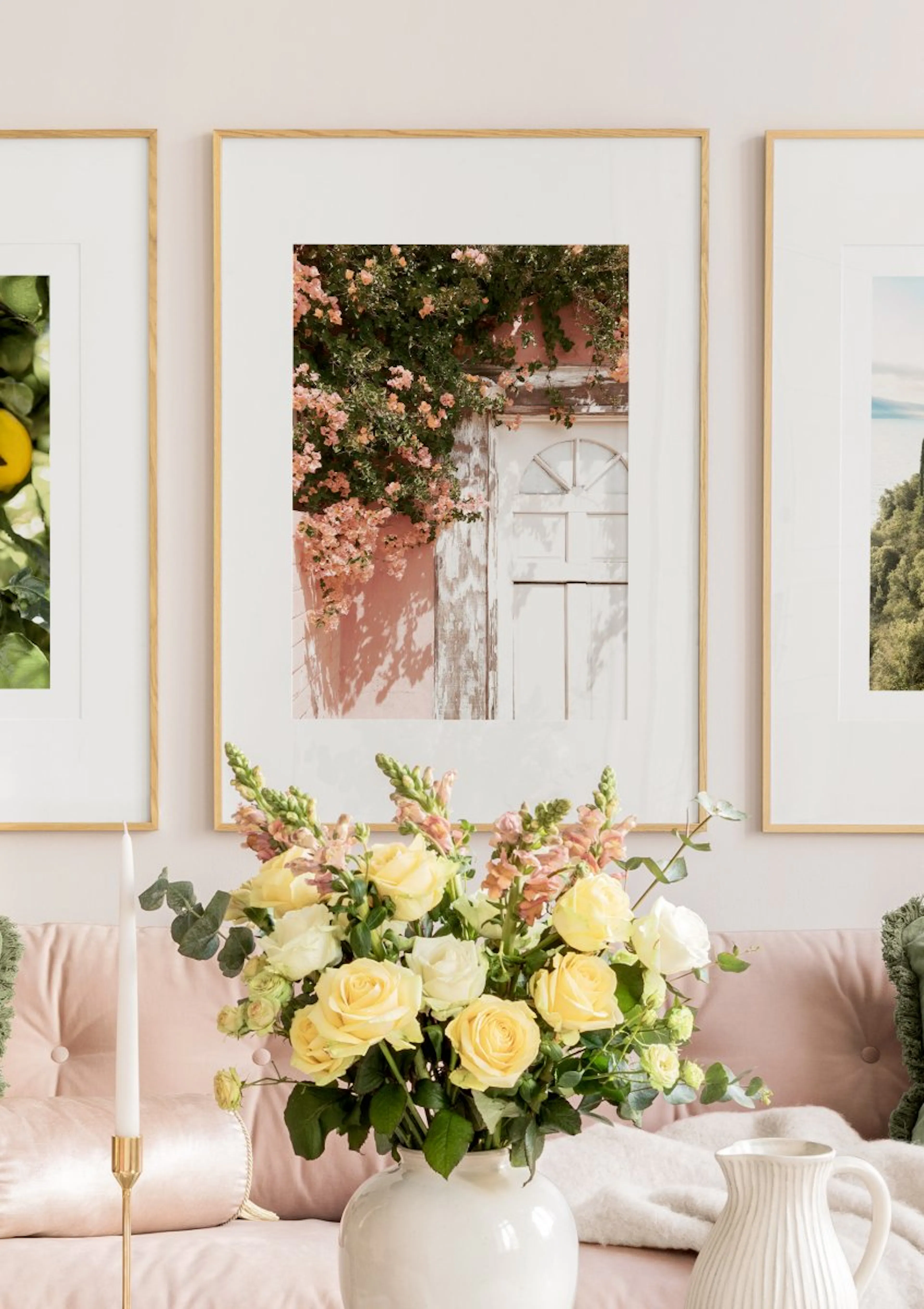 Poster di una porta bianca circondata da rose pesca e piante verdi, appeso sopra un divano rosa con fiori.