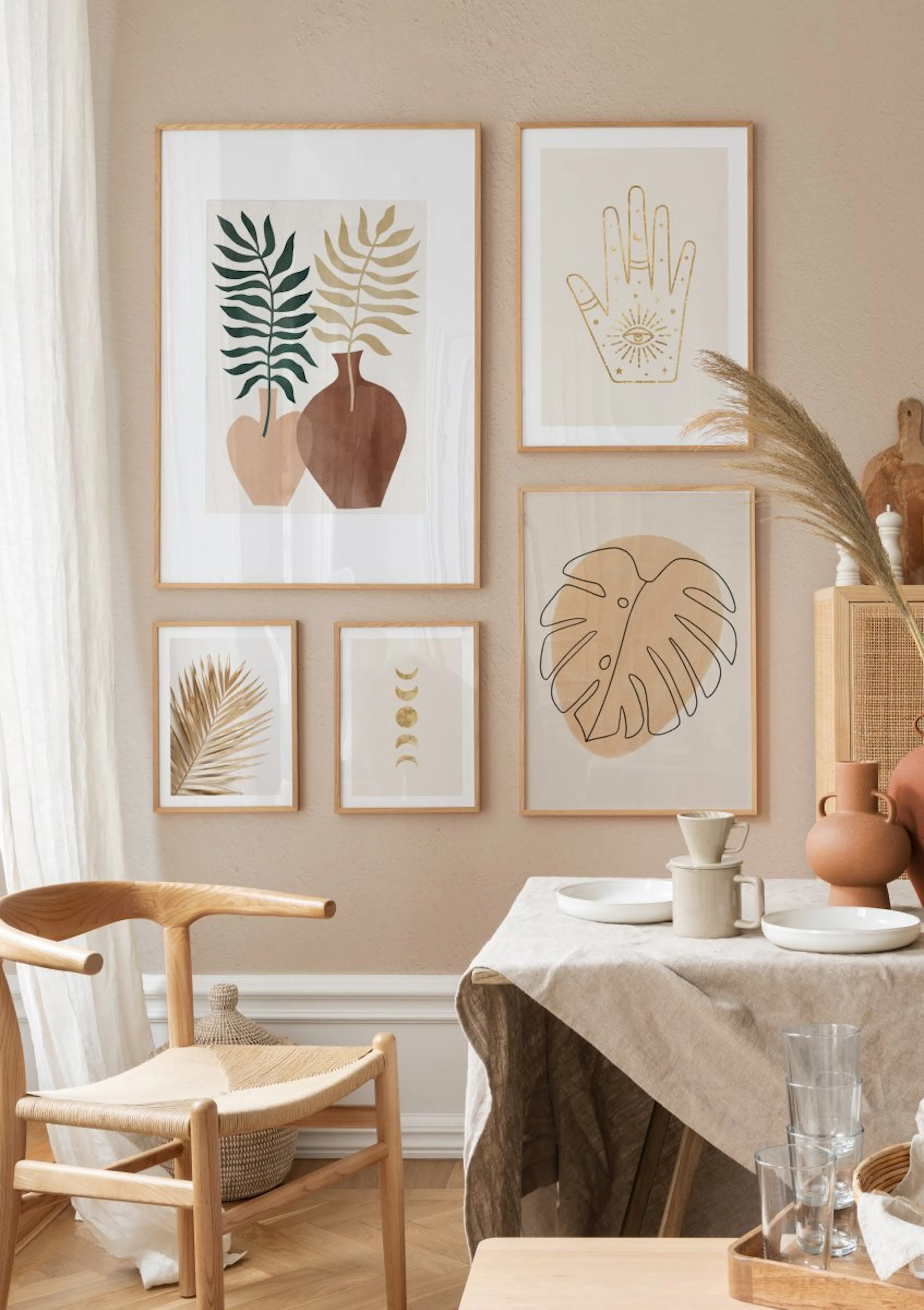 A gallery wall of five posters in a dining room featuring botanical and spiritual designs in warm, earthy tones.