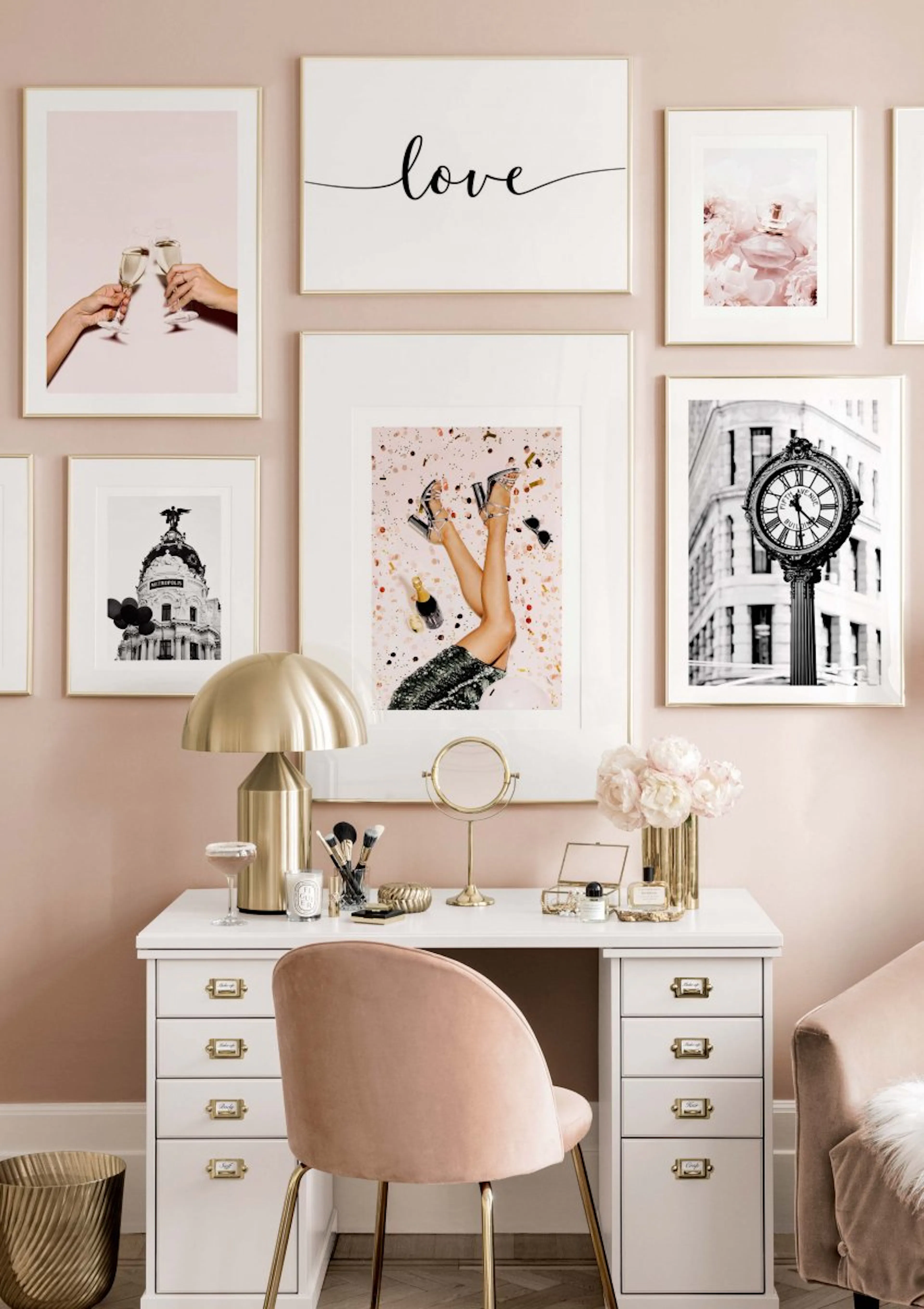 A gallery wall with six posters above a white desk. Posters feature champagne, love script, perfume, legs with heels, and a buil