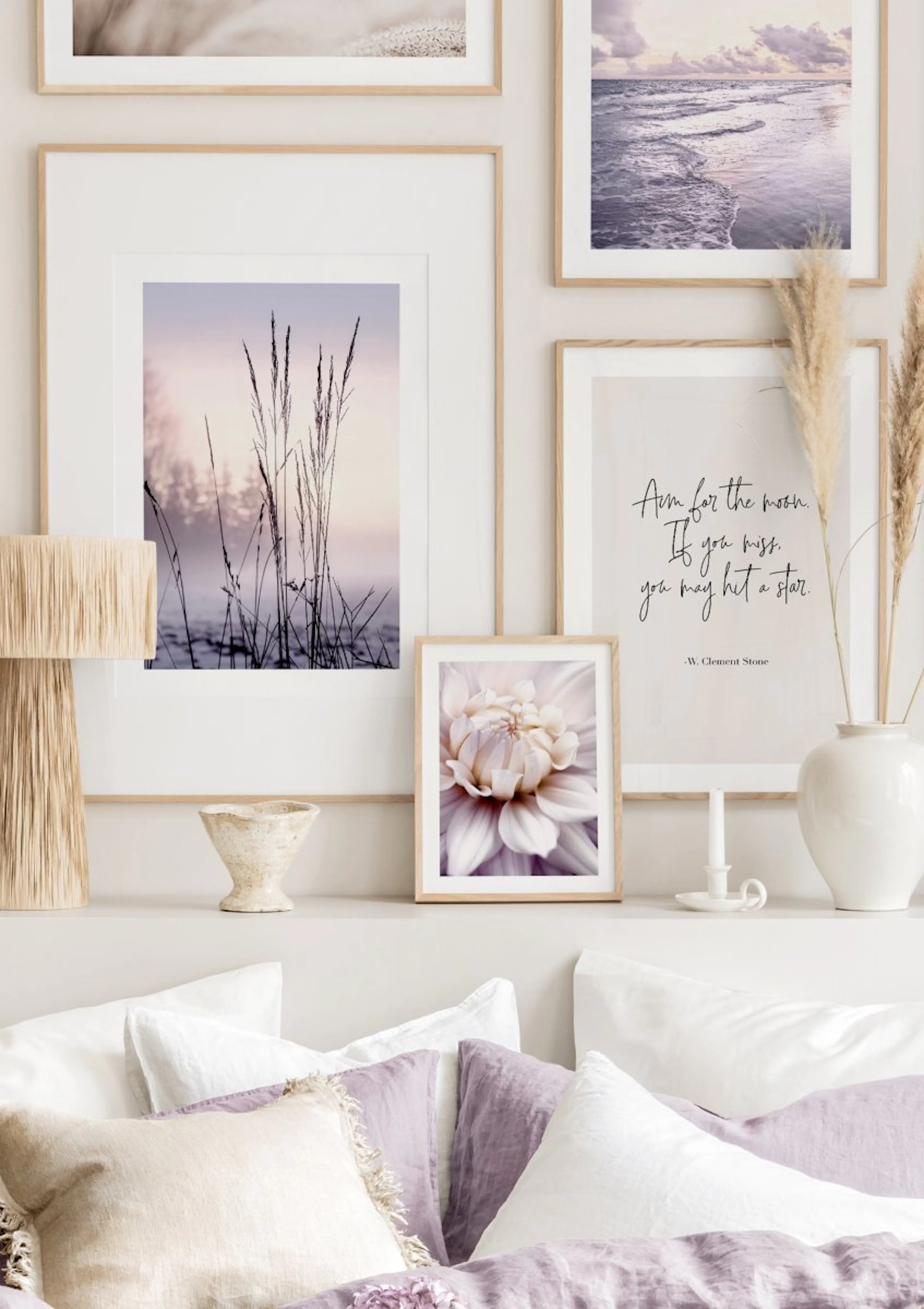 A gallery wall of nature and inspirational posters displayed above a bed with white and purple pillows.