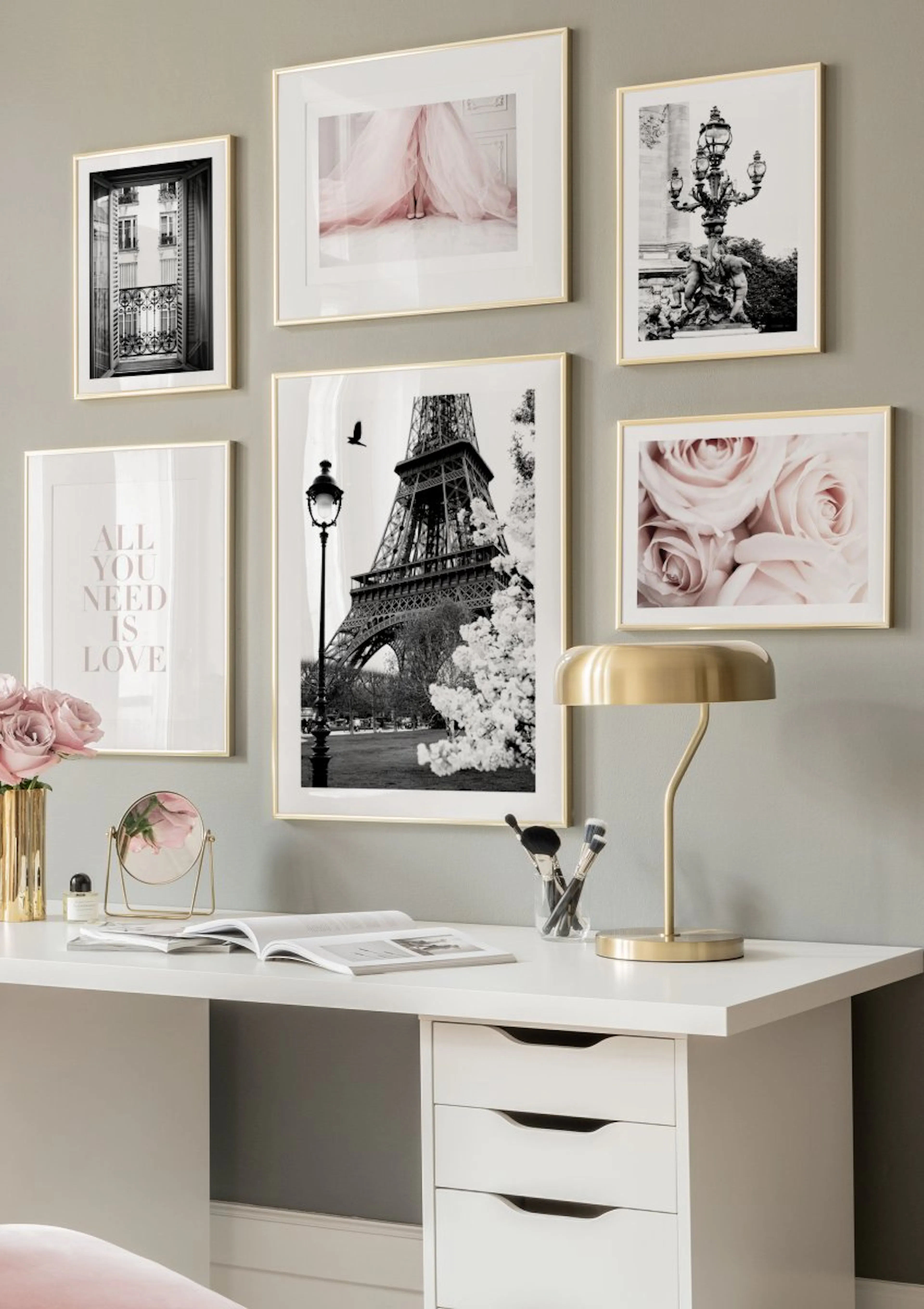 A gallery wall of Paris-themed and romantic prints, including the Eiffel Tower and pink roses, above a white desk.