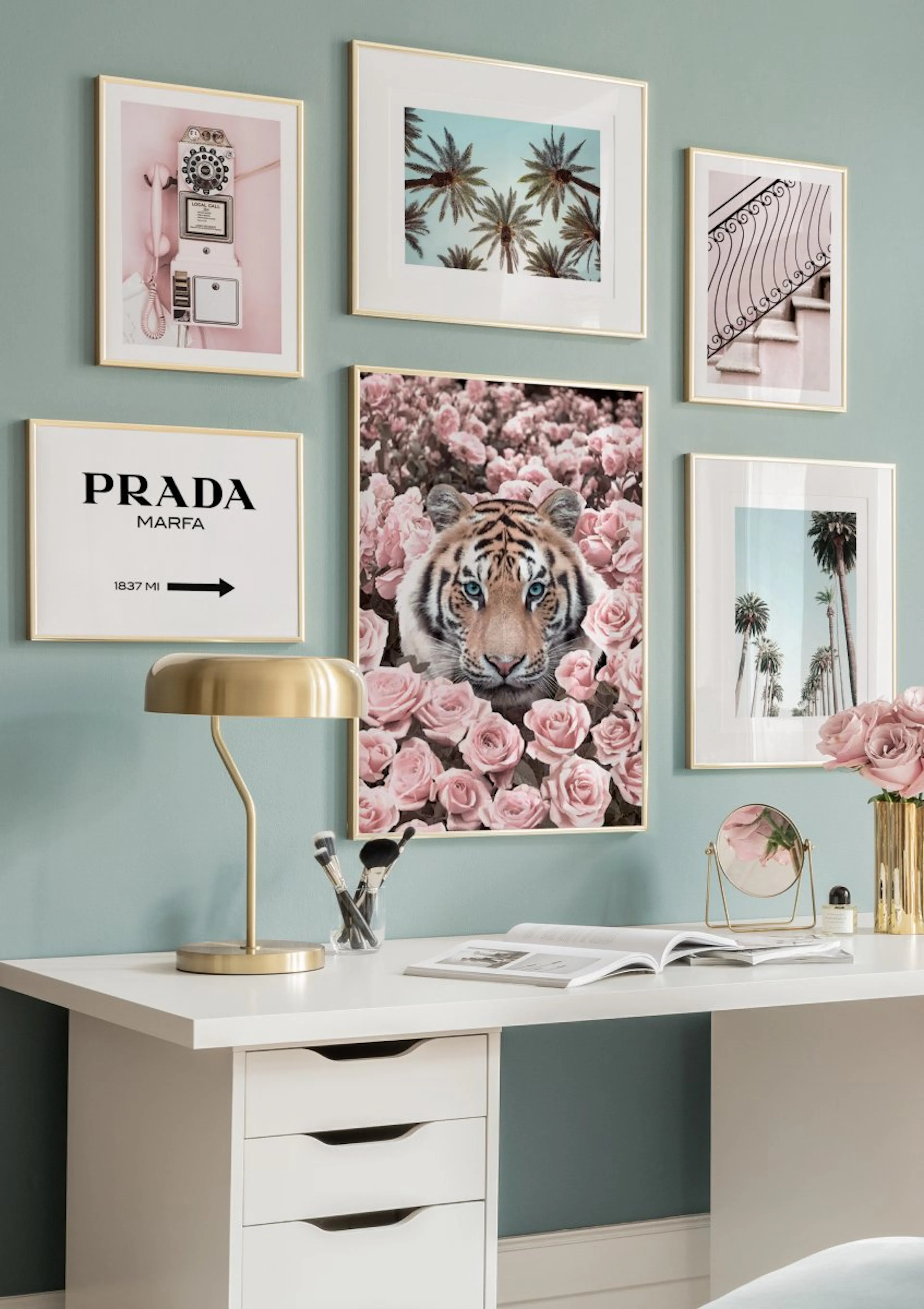 Galleria a parete con poster di tigre, palme e telefono rosa, su una scrivania bianca.