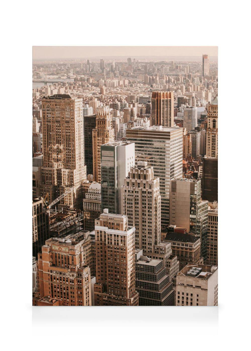En canvastavla som visar New Yorks skyline med många höga byggnader i varmt ljus.