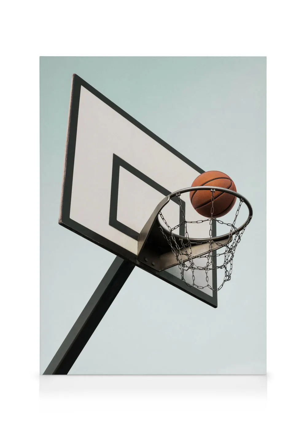A canvas showing a basketball about to go through a hoop with a metal chain net against a pale blue sky.