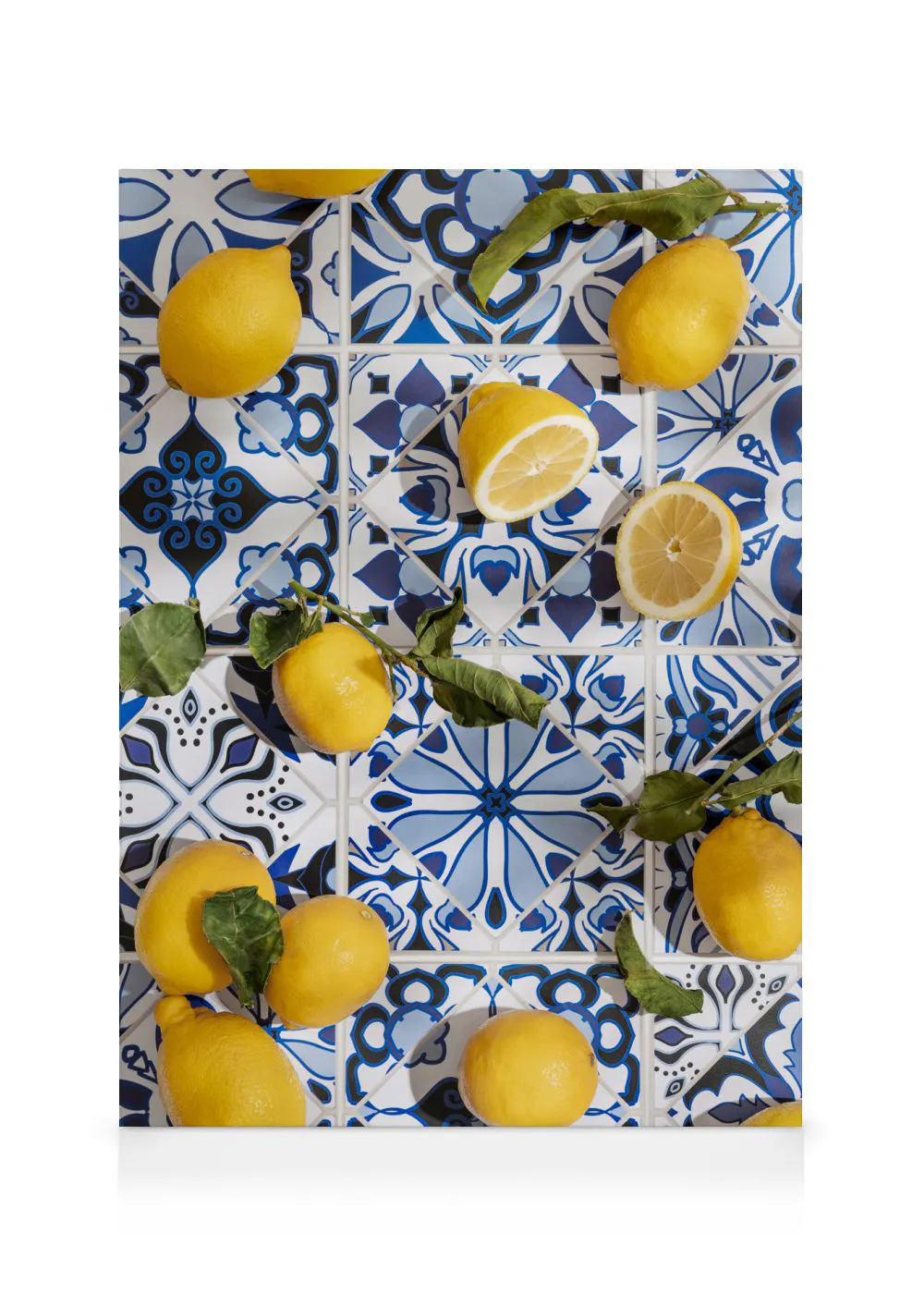 A canvas displaying bright yellow lemons and lemon halves with green leaves on blue and white patterned tiles.