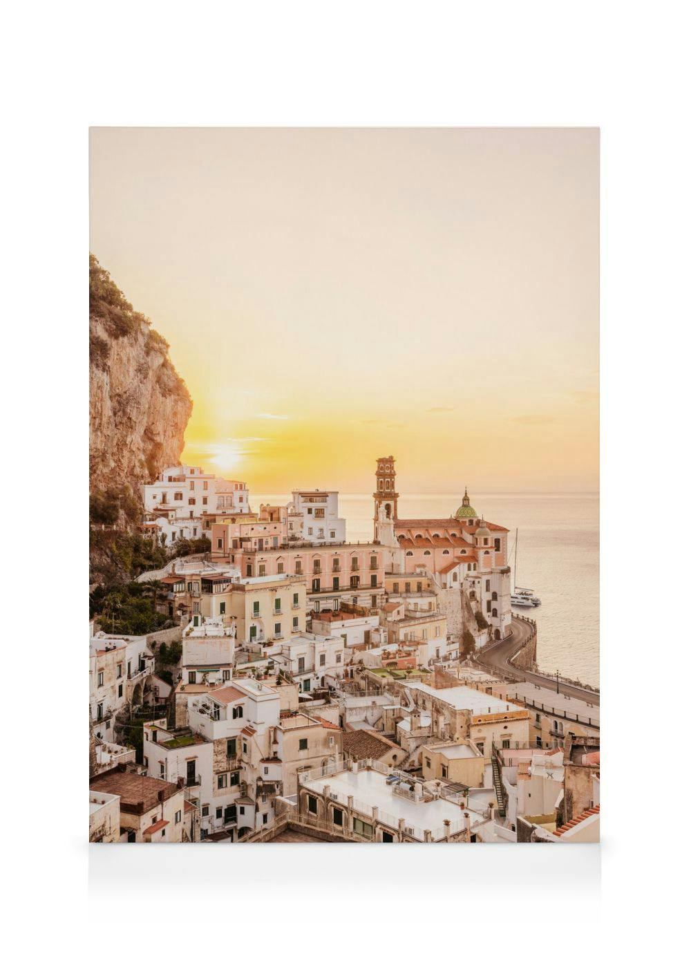 Een canvas met een panoramisch beeld van de kustplaats Amalfi bij zonsondergang, met gebouwen tegen een klif en de zee.