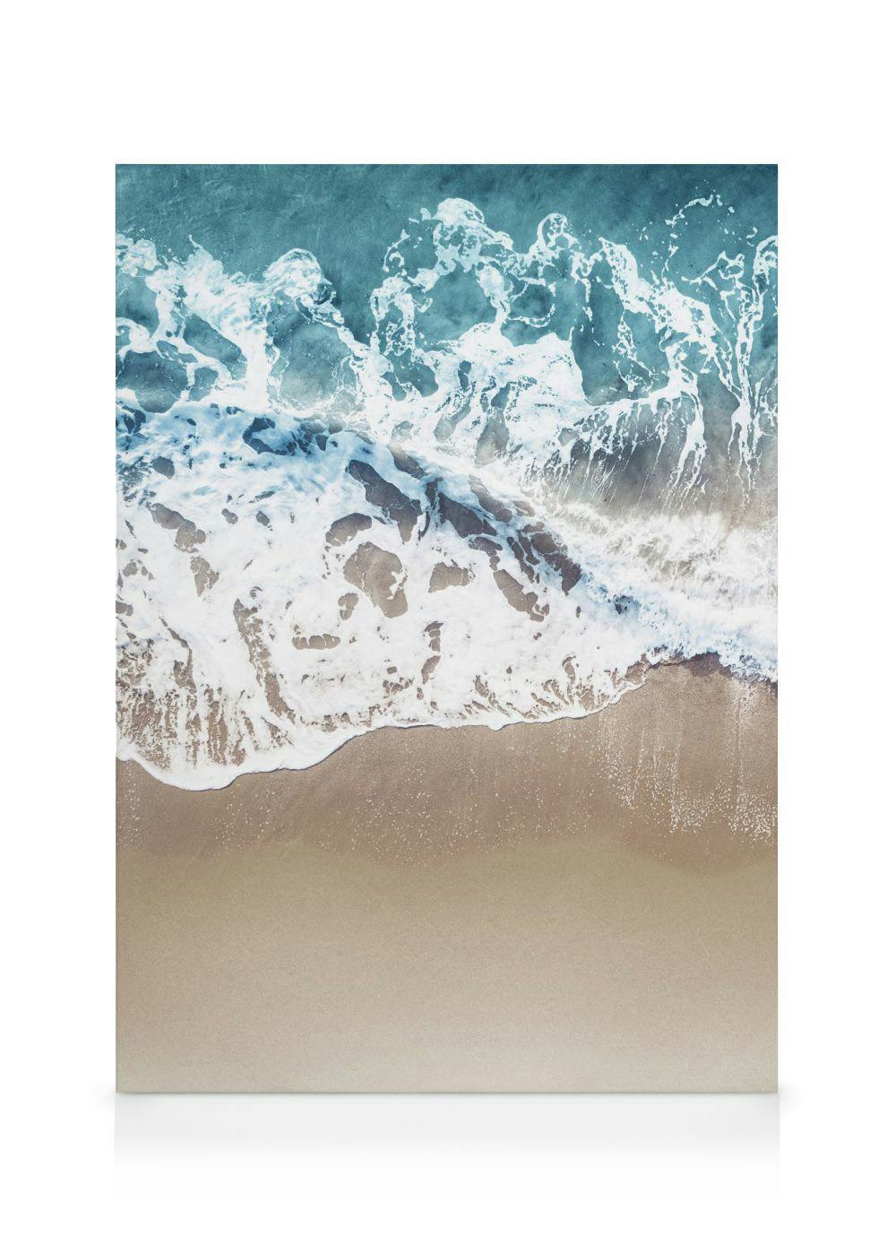 Een canvas van een strand met turquoise water, witte schuimende golven en goudkleurig zand, gezien van bovenaf.