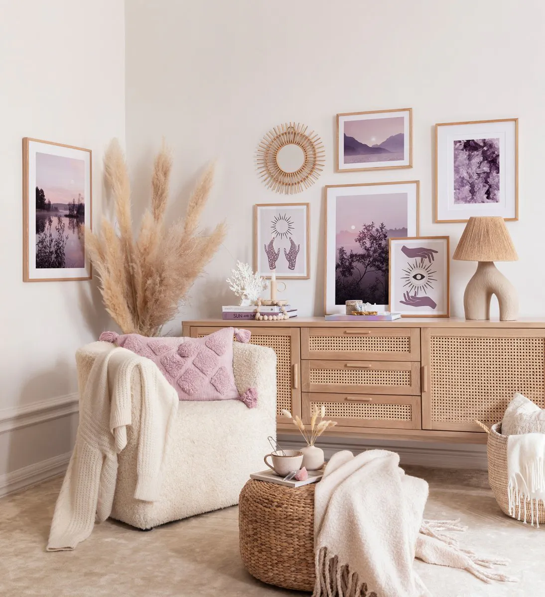 A gallery wall of posters in a living room, featuring mystical hands, abstract purple, a lake, and a tree at dusk.