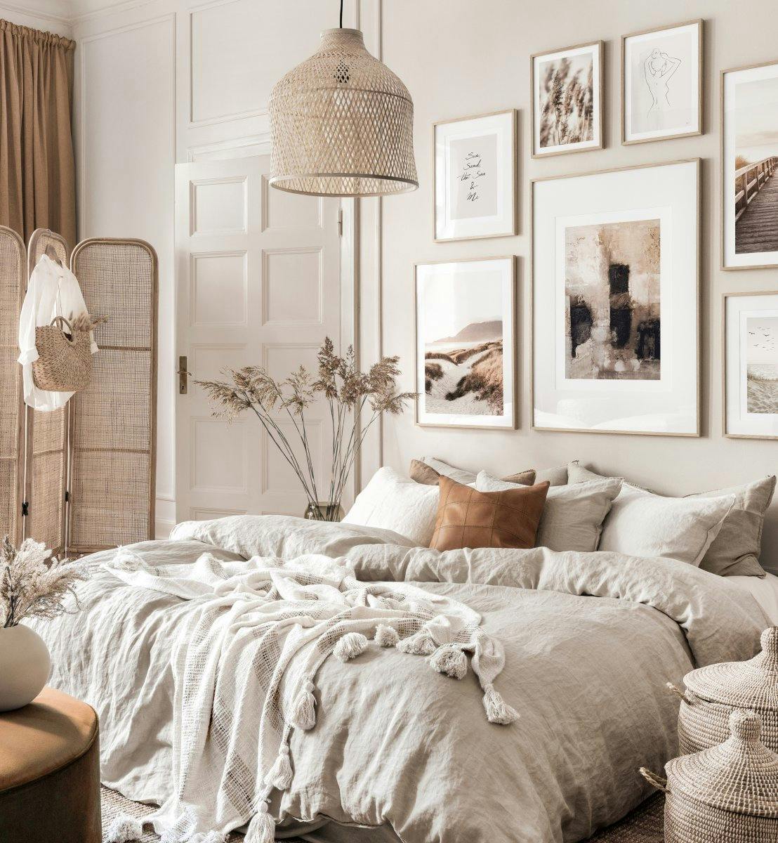 Un poster astratto con blocchi scuri e pennellate chiare su sfondo beige, parte di una galleria a parete in camera da letto.