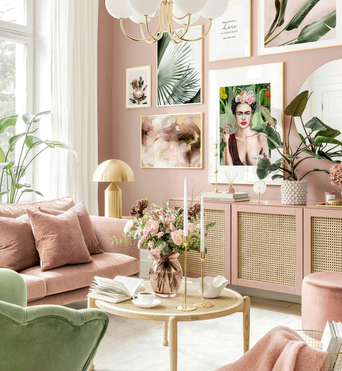 Poster dune pièce de vie rose avec un canapé et plusieurs affiches de fleurs et de feuilles tropicales sur le mur.