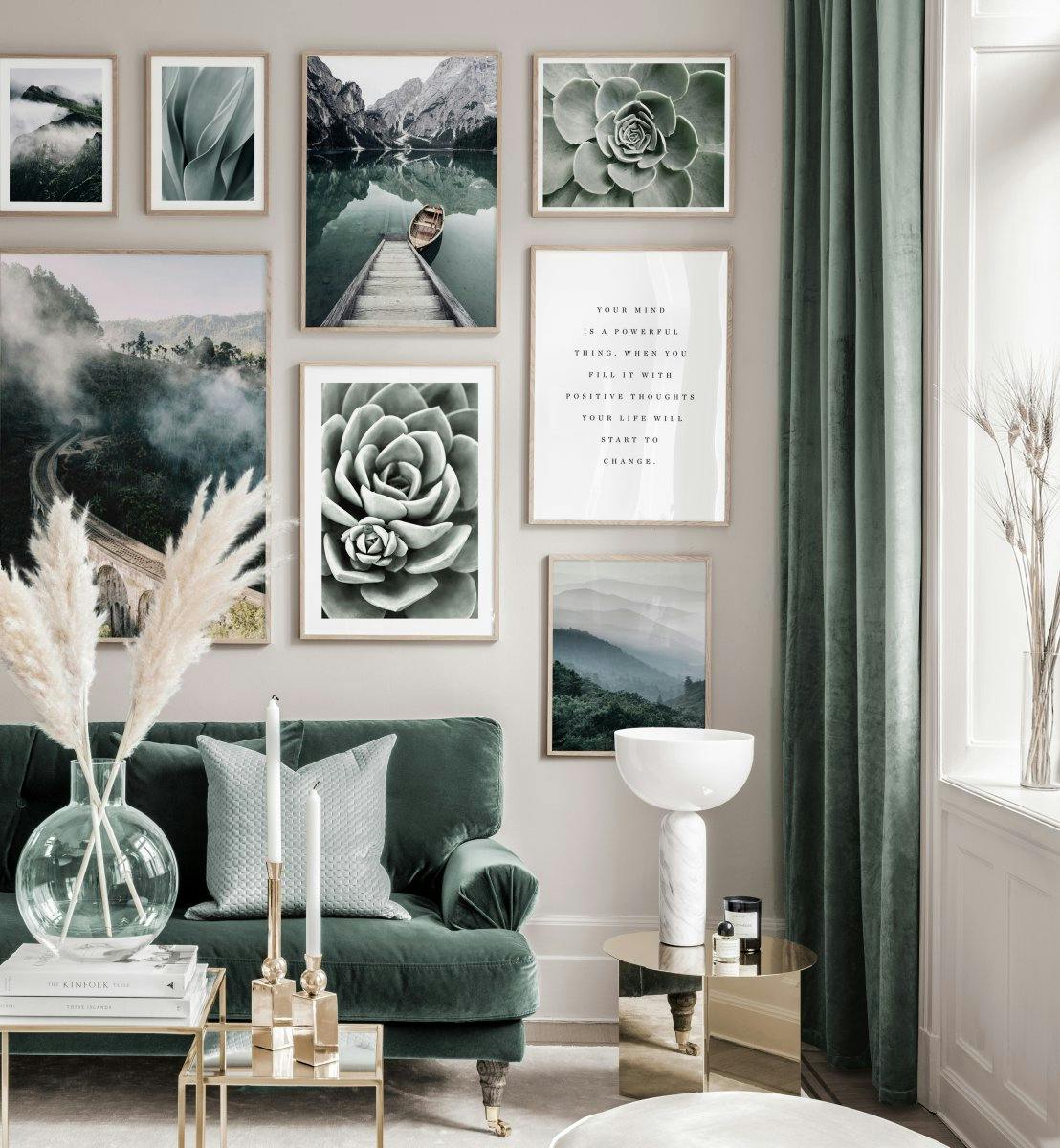 Sisustuskuva, jossa vihreä sohva ja useita julisteita. Julisteissa on kuvia vuoristomaisemista, sukkulenteista ja tekstiä.