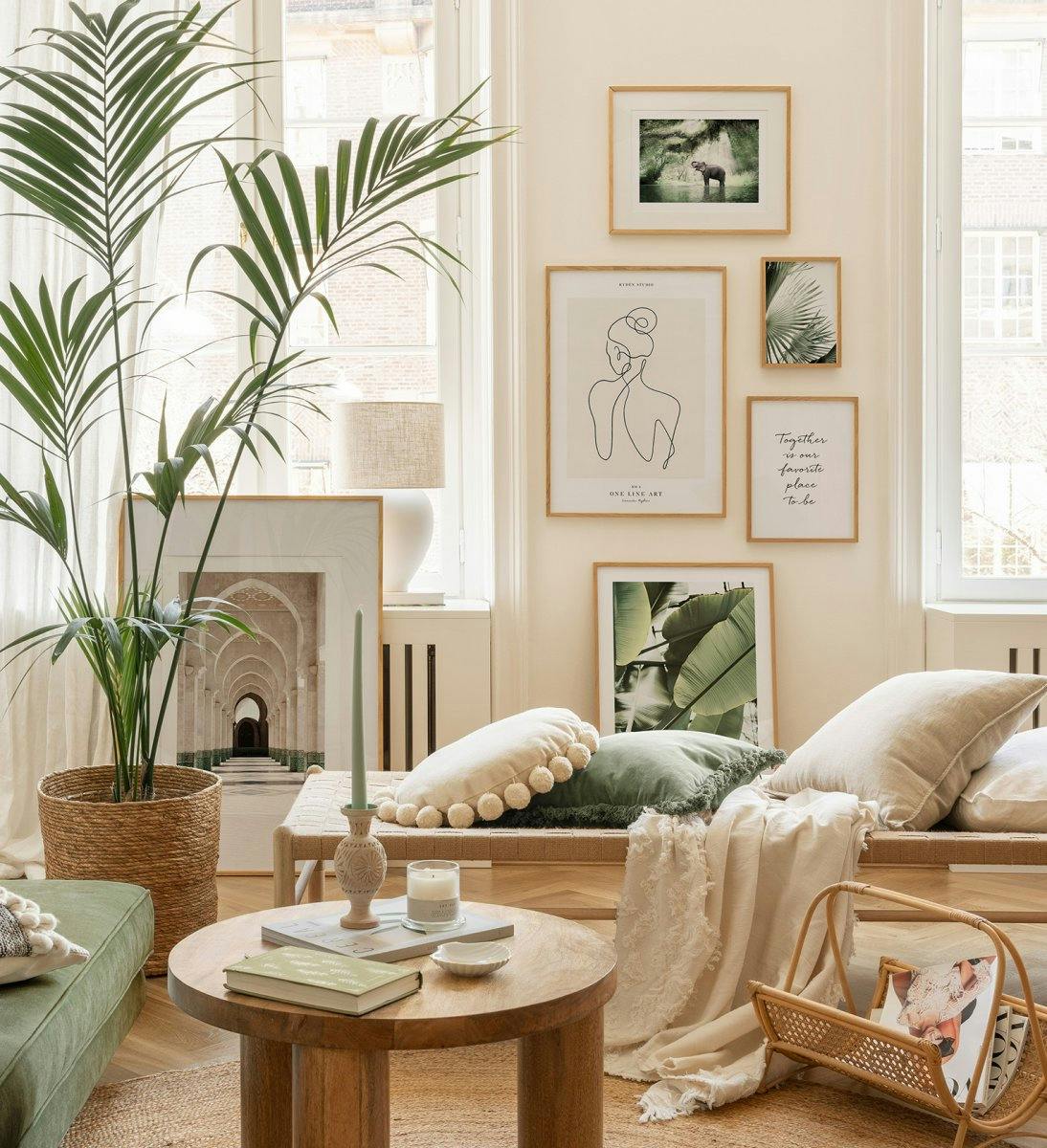 A poster gallery wall featuring an elephant, a line art woman, palm fronds, banana leaves, and a text poster in a bright living