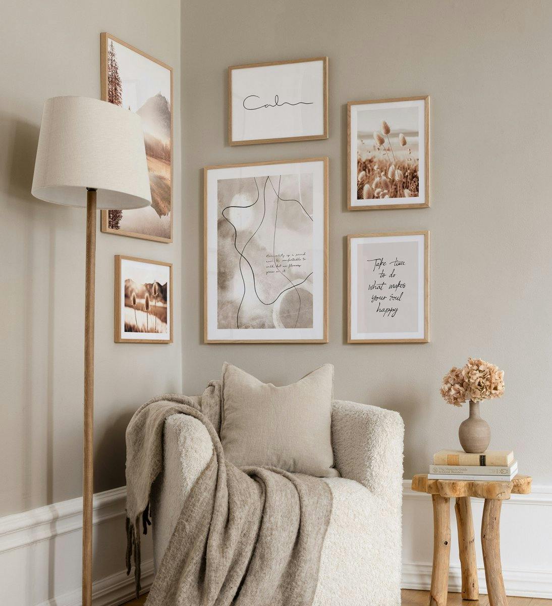 A gallery wall with five posters, including a landscape, pampas grass, abstract lines, Calm in script, and Take time to do what