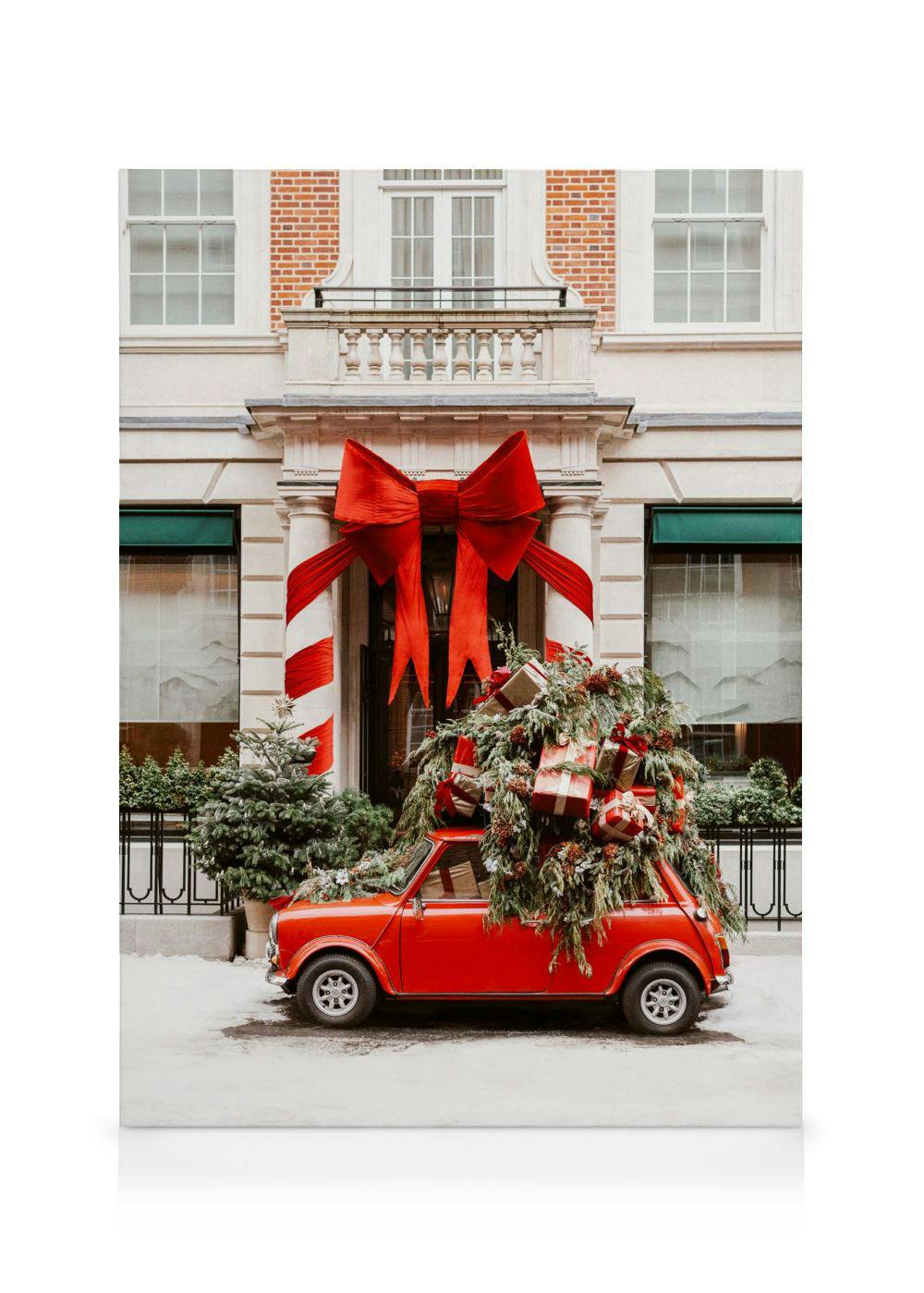 Leinwandbild eines roten Vintage-Autos mit Weihnachtsbaum und Geschenken vor einem festlich geschmückten Gebäude.