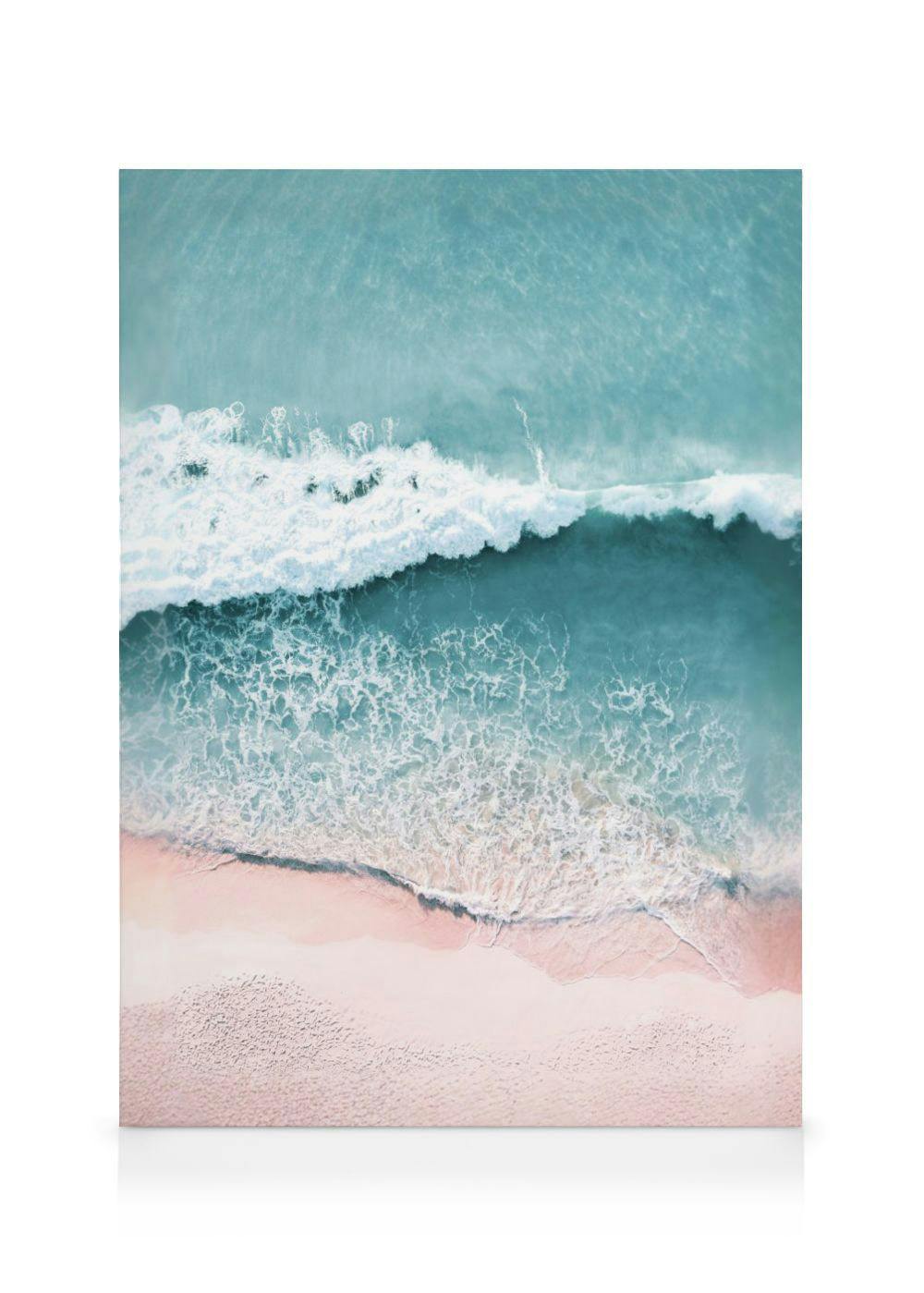 An aerial view canvas of turquoise ocean waves crashing onto a light pink sand beach.