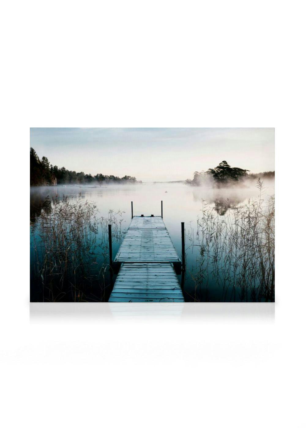 Leinwandbild einer Holzbrücke, die in einen nebligen See mit Schilf und im Hintergrund sichtbaren Bäumen führt.
