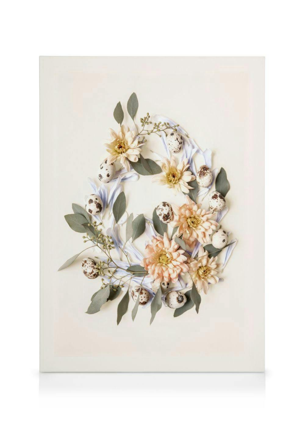 Een canvas met een lentekrans van bloemen, eucalyptusbladeren en kwarteleitjes op een lichte achtergrond.