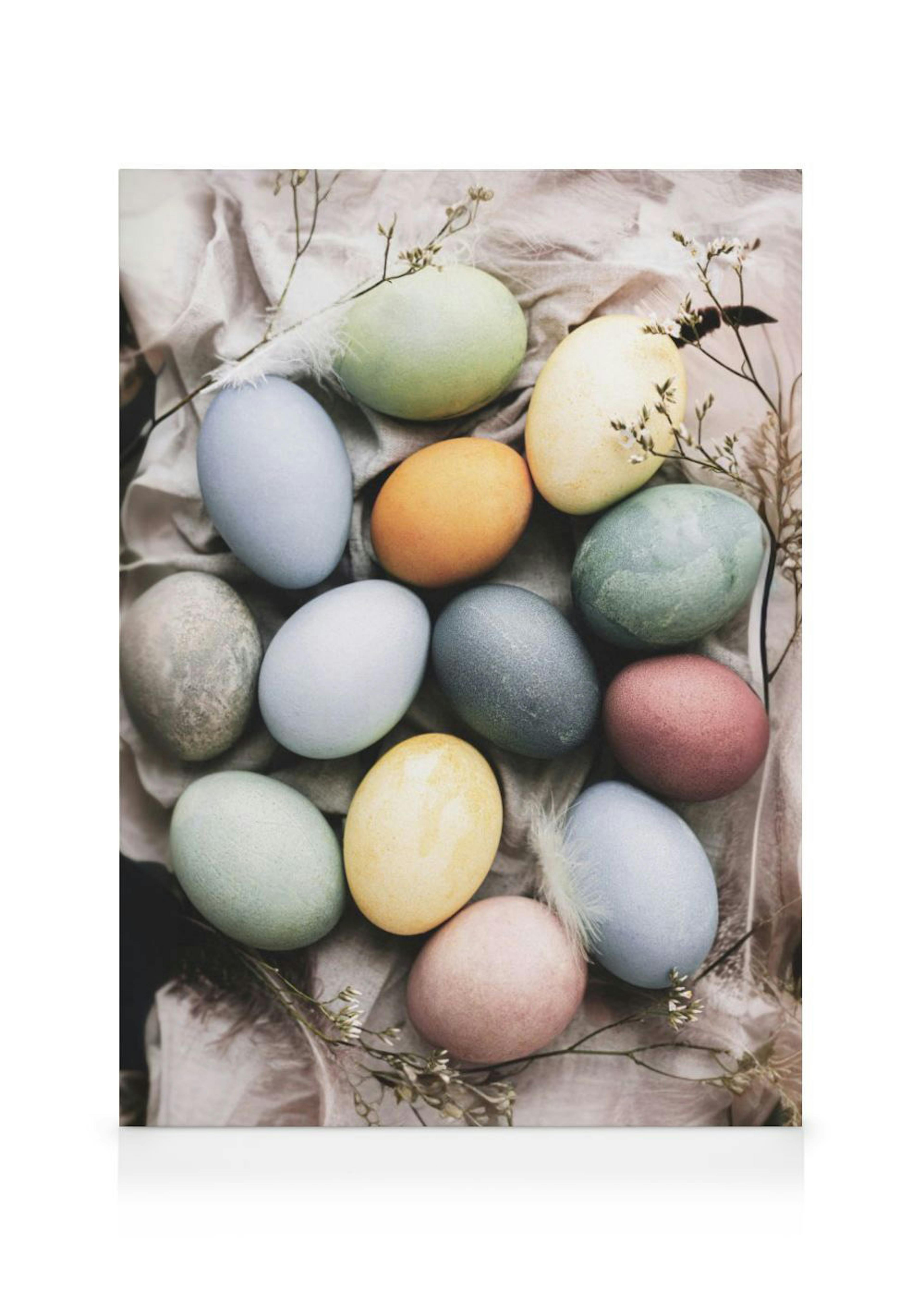 A canvas displaying pastel-coloured Easter eggs in shades of blue, green, yellow, pink, and orange nestled on a neutral fabric w