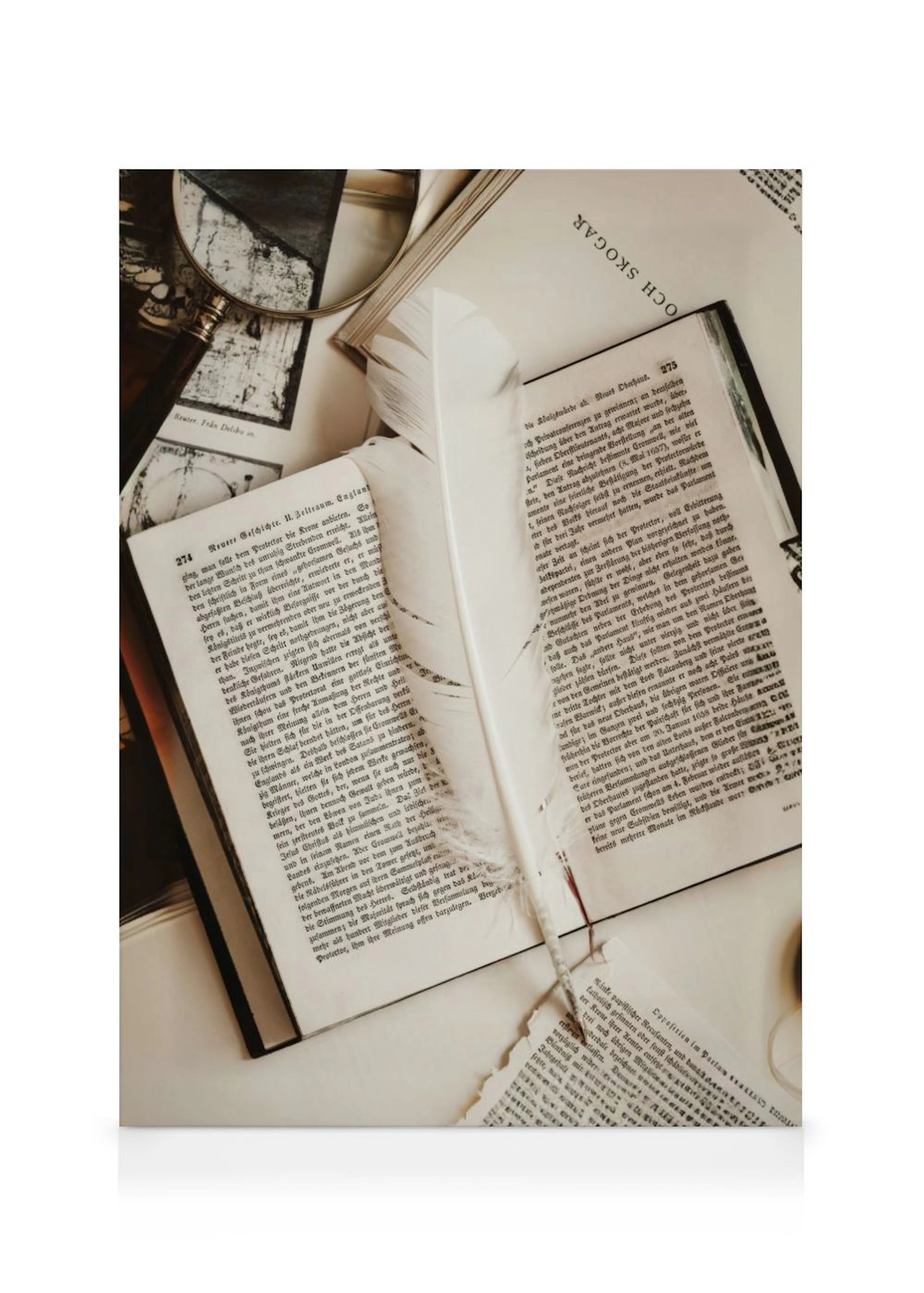 A canvas showing an overhead view of open antique books, a white feather, torn paper, and a magnifying glass.