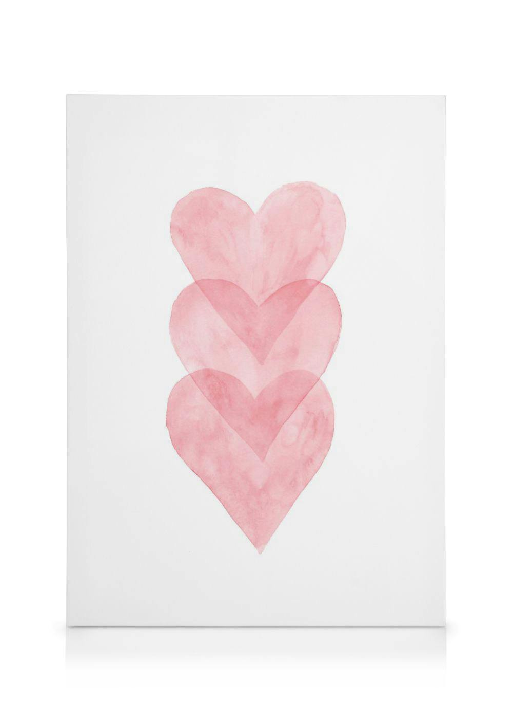 Lienzo con tres corazones de acuarela rosa superpuestos verticalmente sobre un fondo blanco.