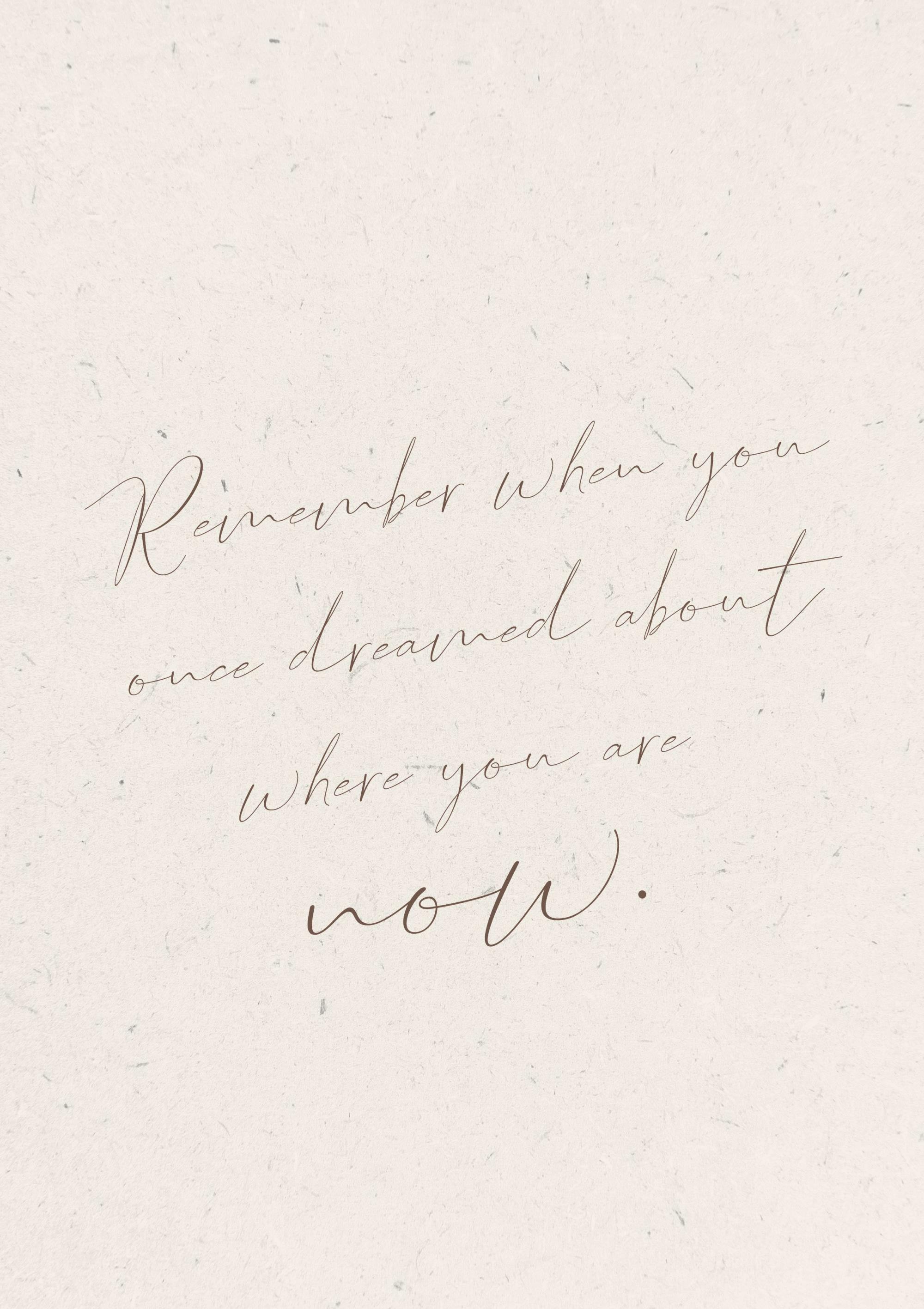 Plakat med inspirerende tekst i brunlig skriveskrift, der siger Remember when you once dreamed about where you are now på en lys