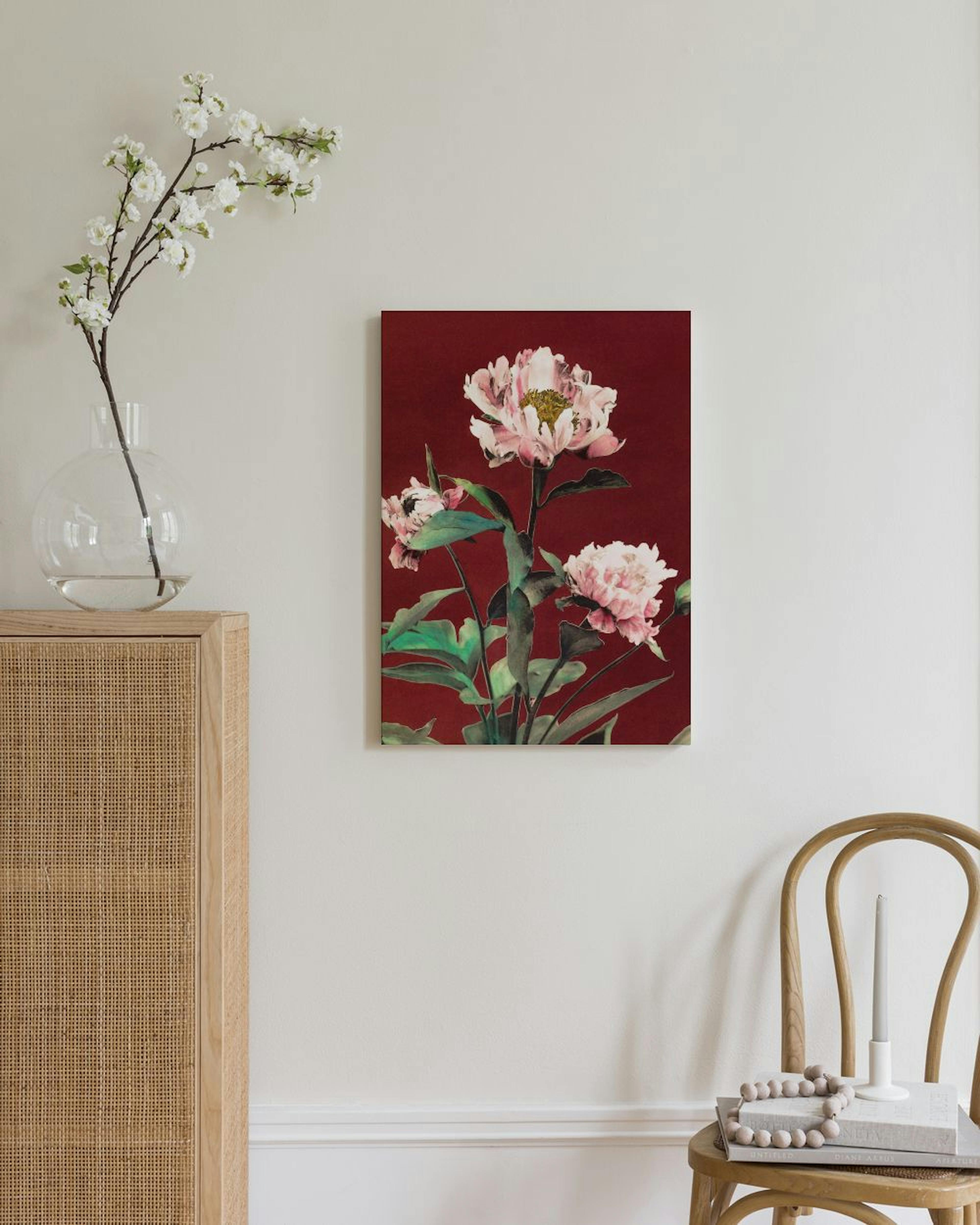 Leinwandbild mit rosa Blüten auf dunkelrotem Hintergrund, hängt in einem hellen Wohnzimmer über einem Stuhl.