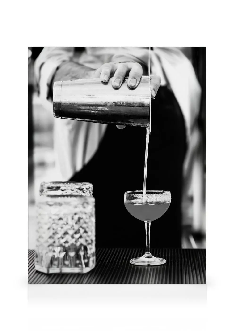 Toile noir et blanc dun barman versant un cocktail dun shaker dans un verre à pied.