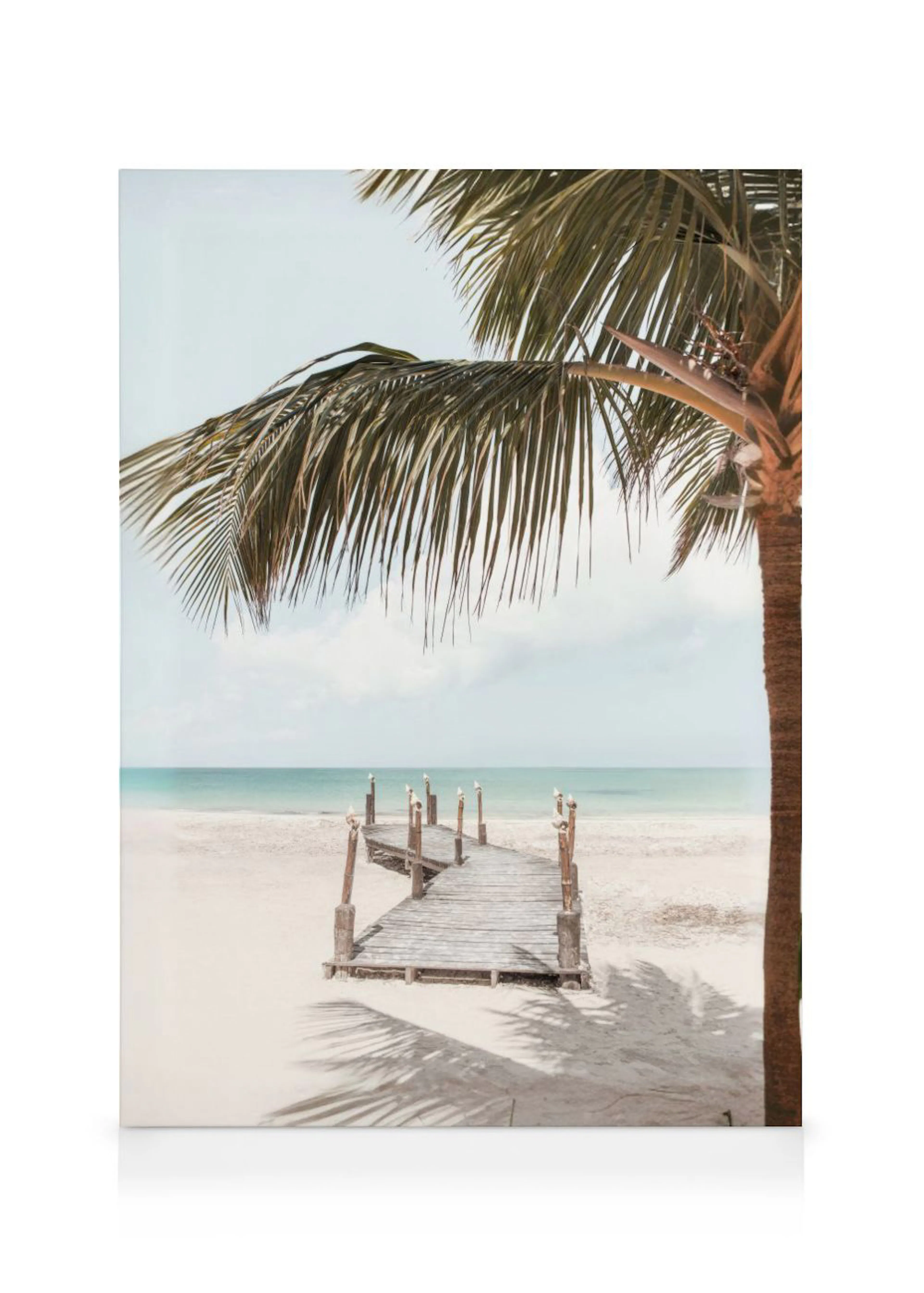 Leinwandbild mit Holzsteg am weißen Sandstrand, türkisfarbenem Meer und Palmenblättern im Vordergrund.