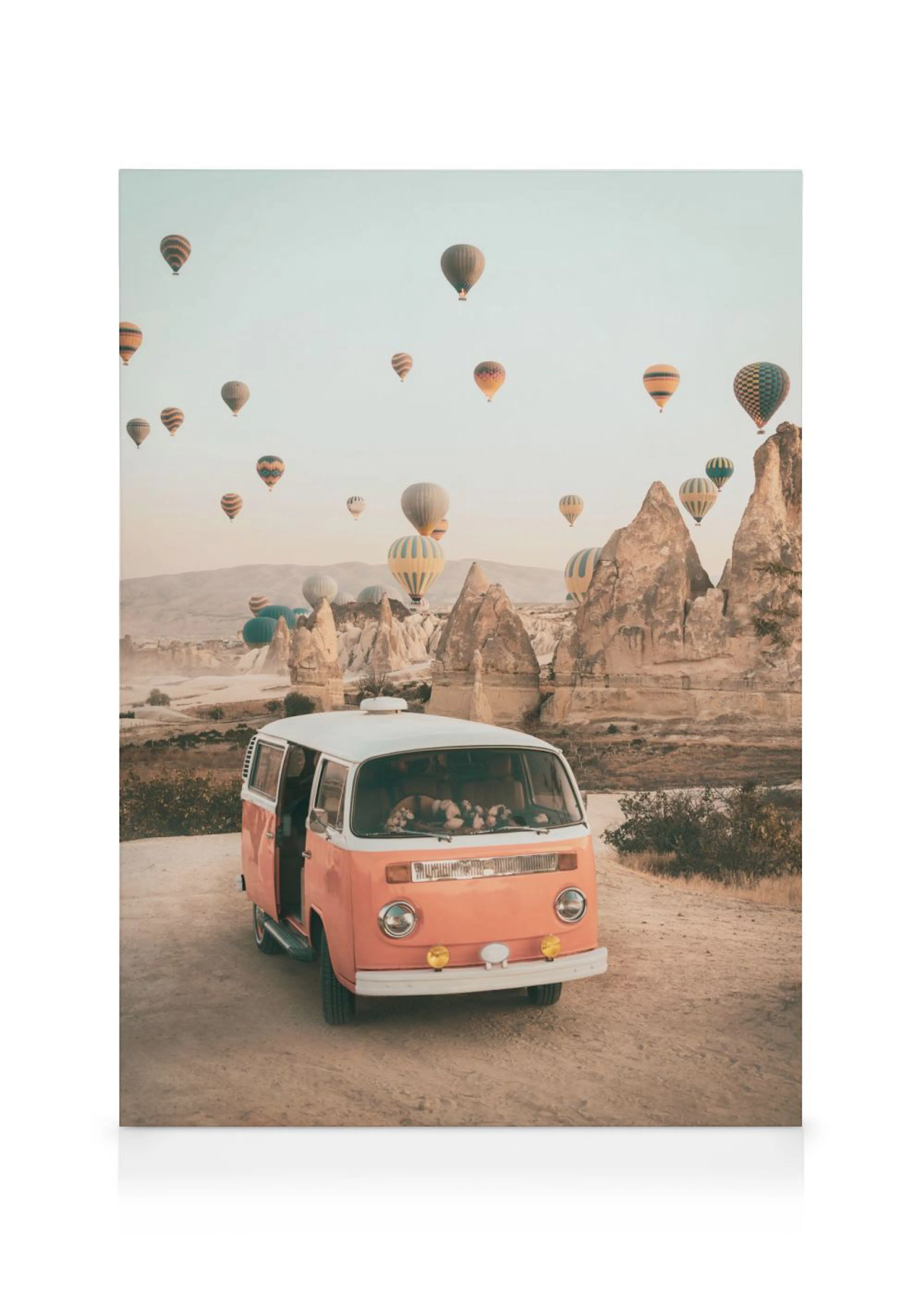 A canvas print of a vintage orange and white camper van with hot air balloons flying over a rocky landscape.