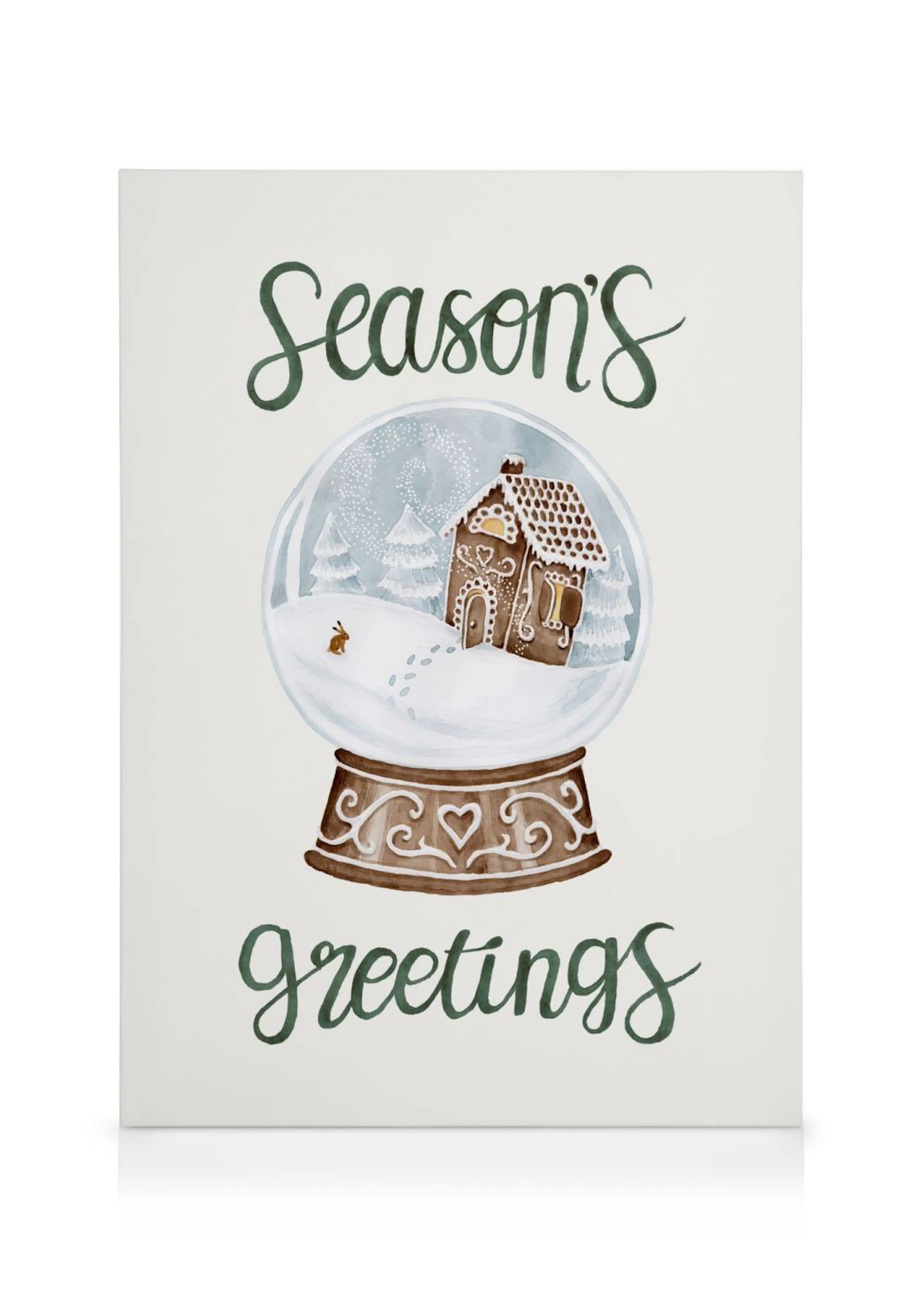 Weihnachtliches Leinwandbild mit einem Lebkuchenhaus in einer Schneekugel, umgeben von Seasons greetings Schriftzug.
